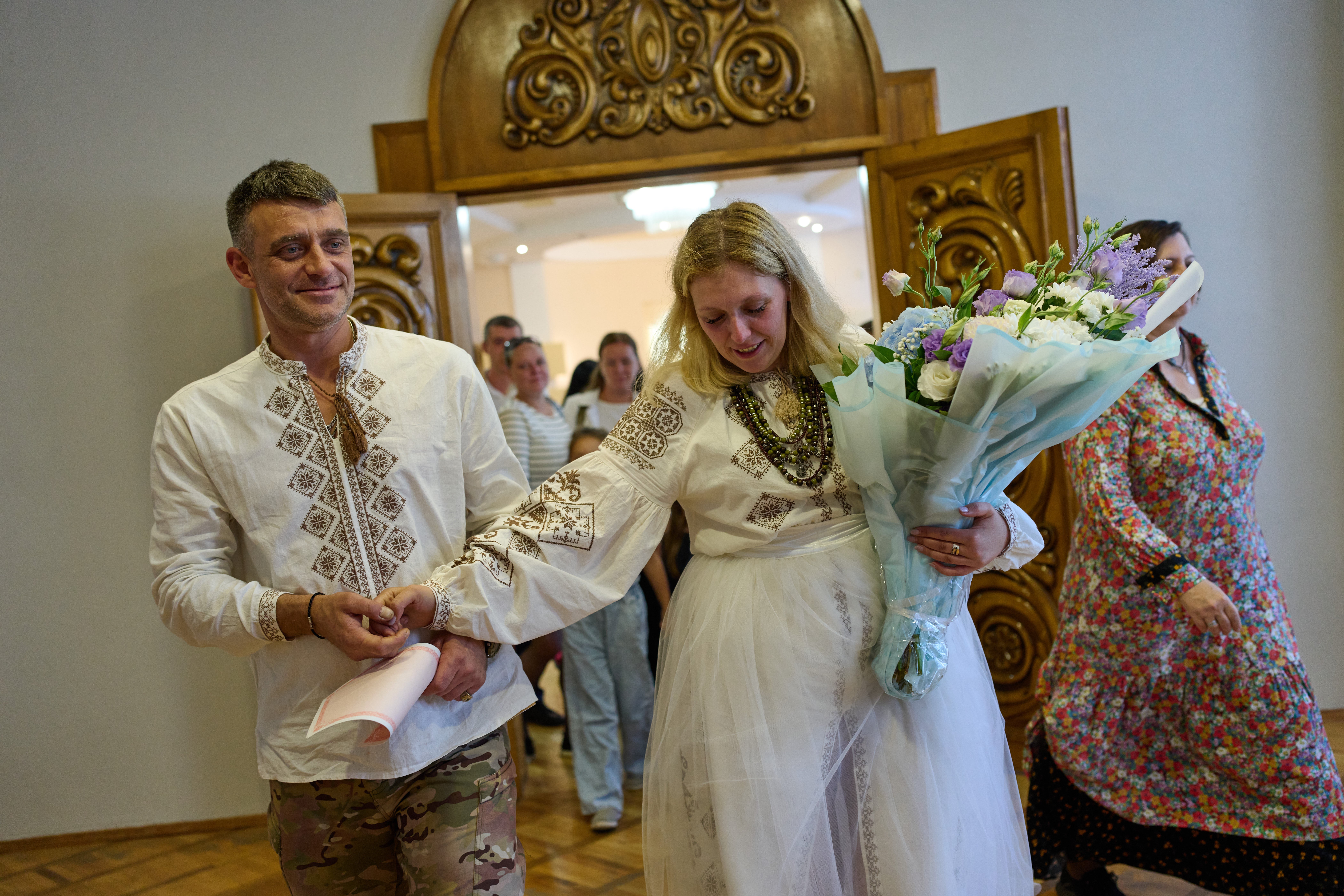 Newly-married couple Liudmyla Ryzhak, right, and her husband Leonid Ryzhak leave after getting married, following a Russian missile and drone attack (Associated Press)