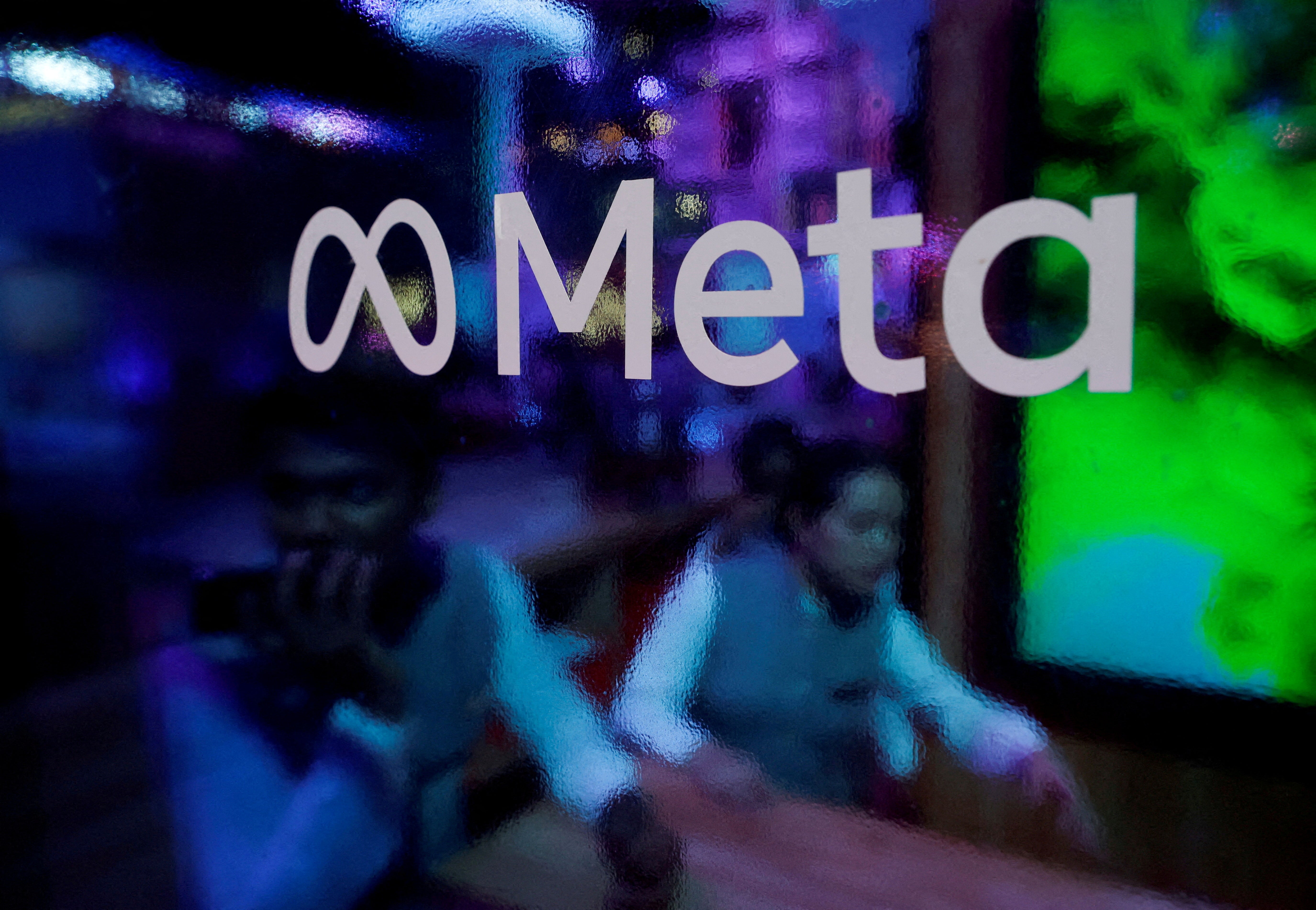 People are seen behind a logo of Meta during a conference in Mumbai (Reuters)