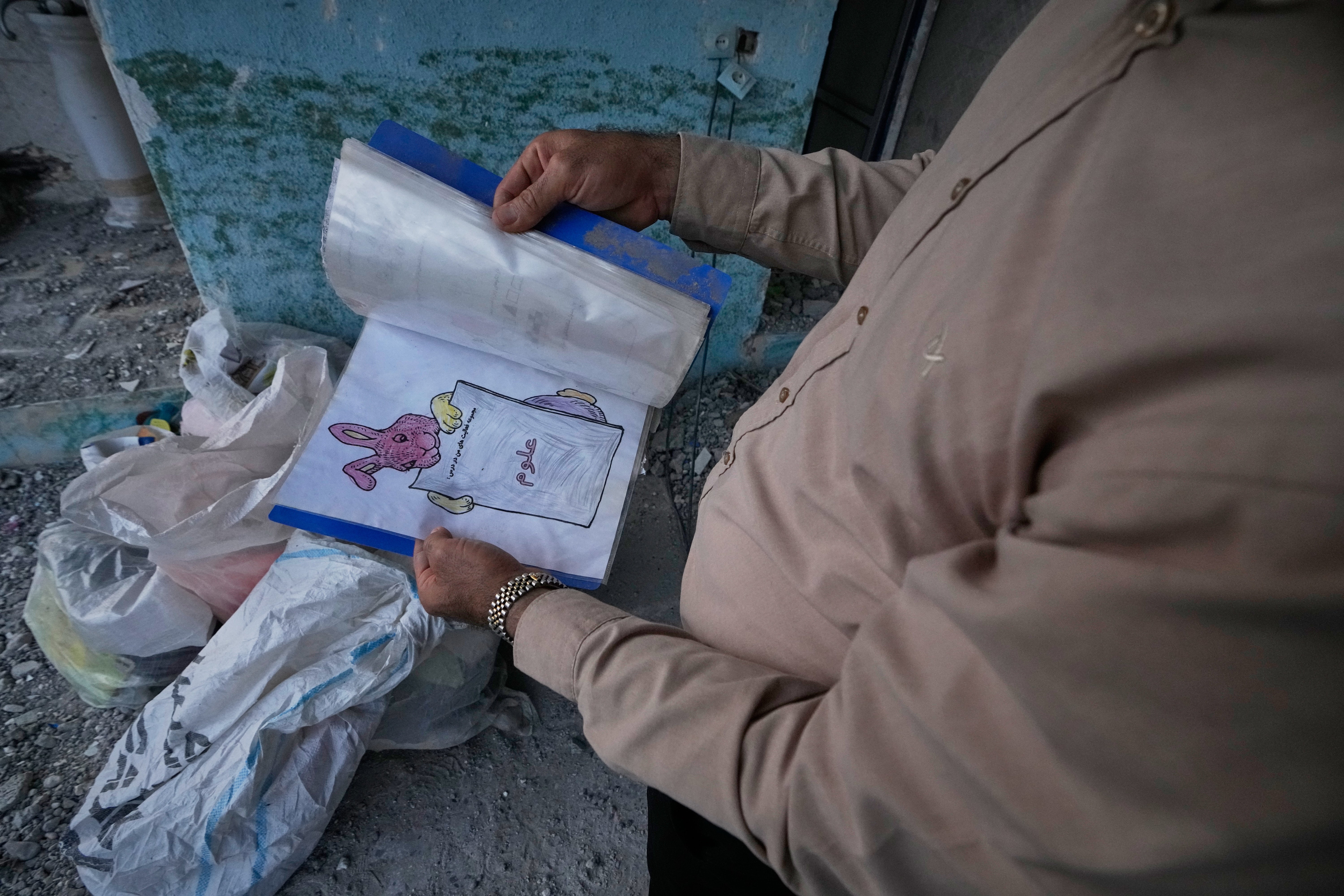 A volunteer holds a child's notebook recovered from the Shajareh Tayyebeh school