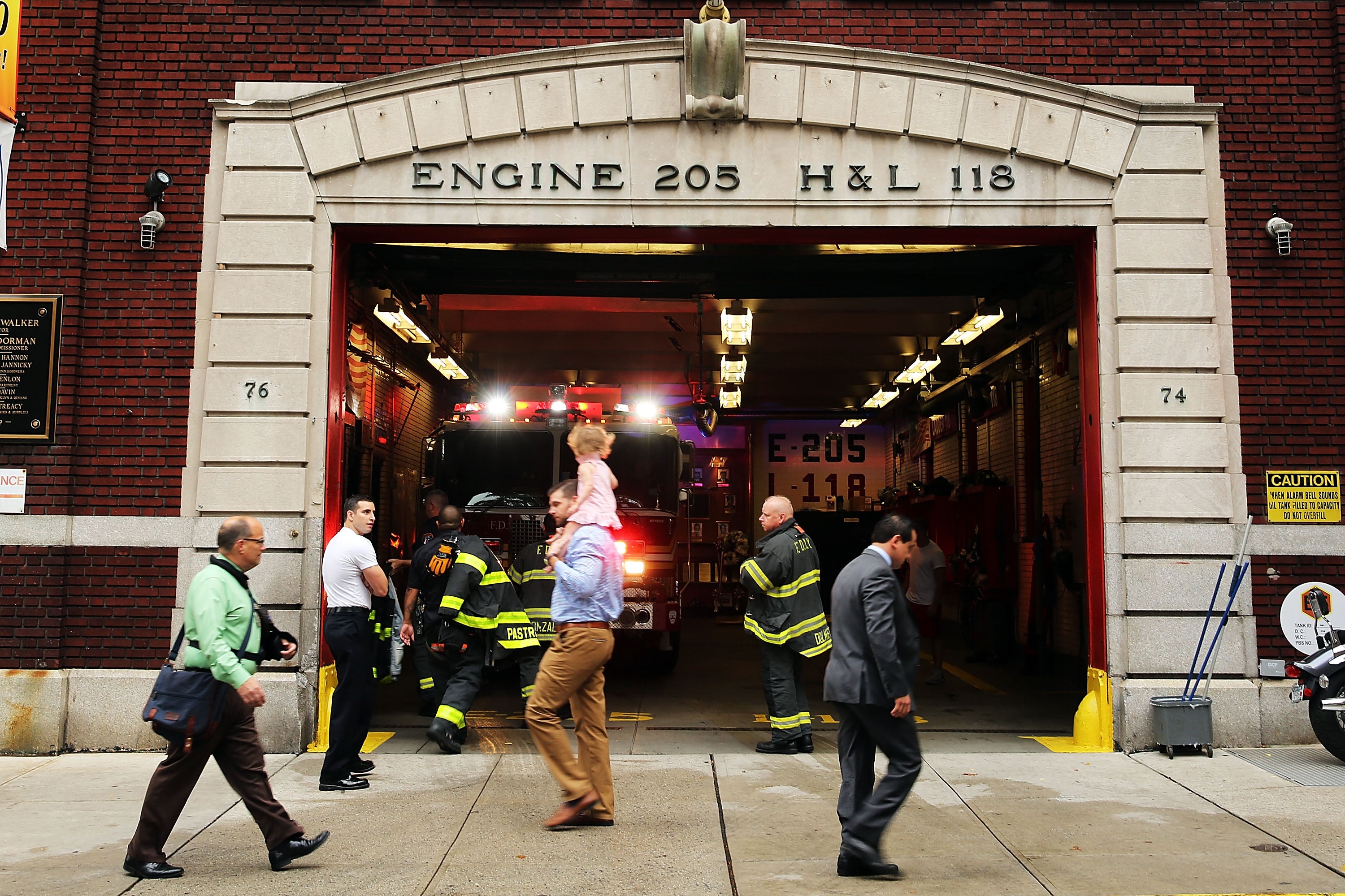 People walk past the Brooklyn firehouse that’s home to the Ladder 118 company