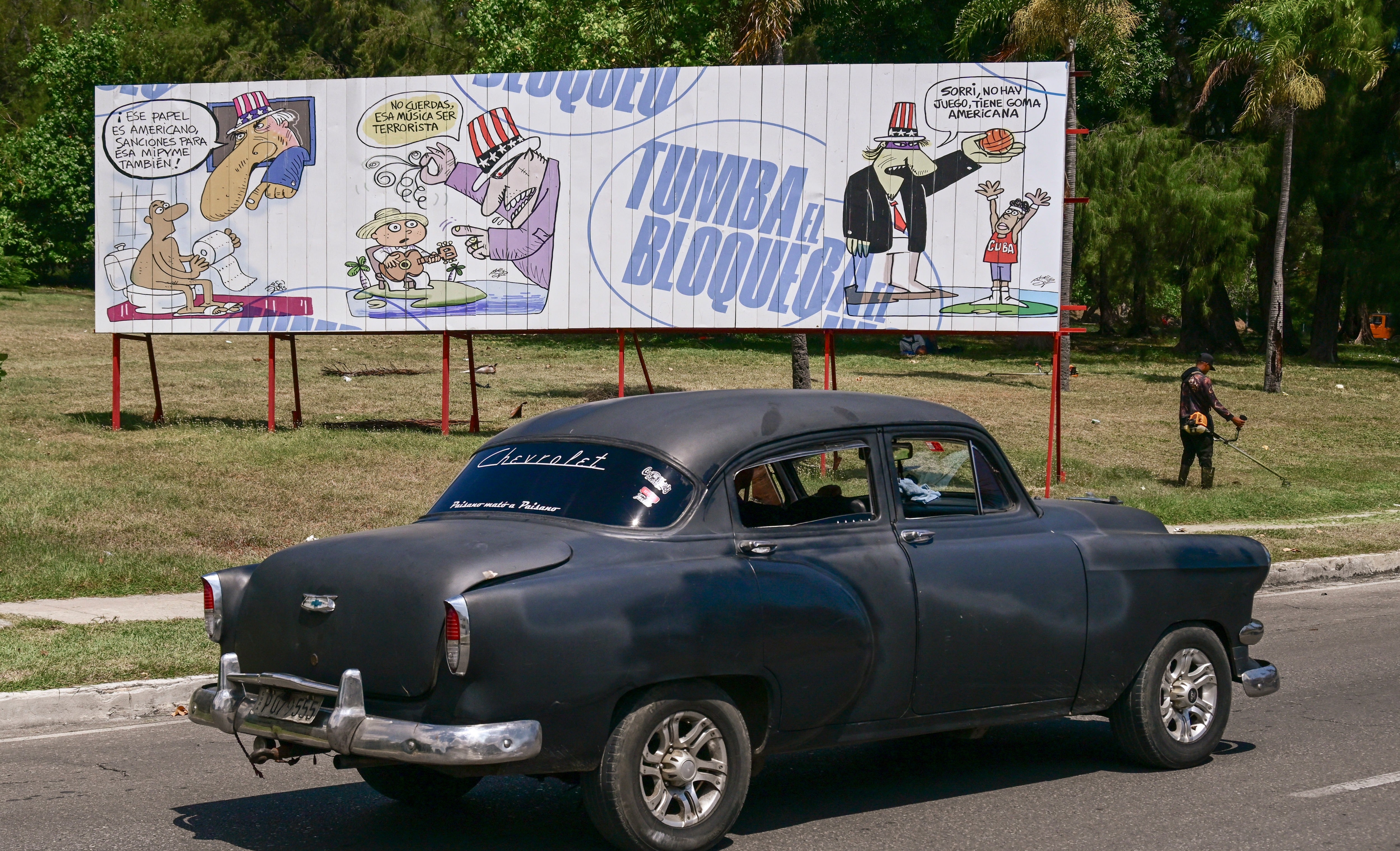 An old car drives past a billboard against the US blockade in Havana on August 25, 2026