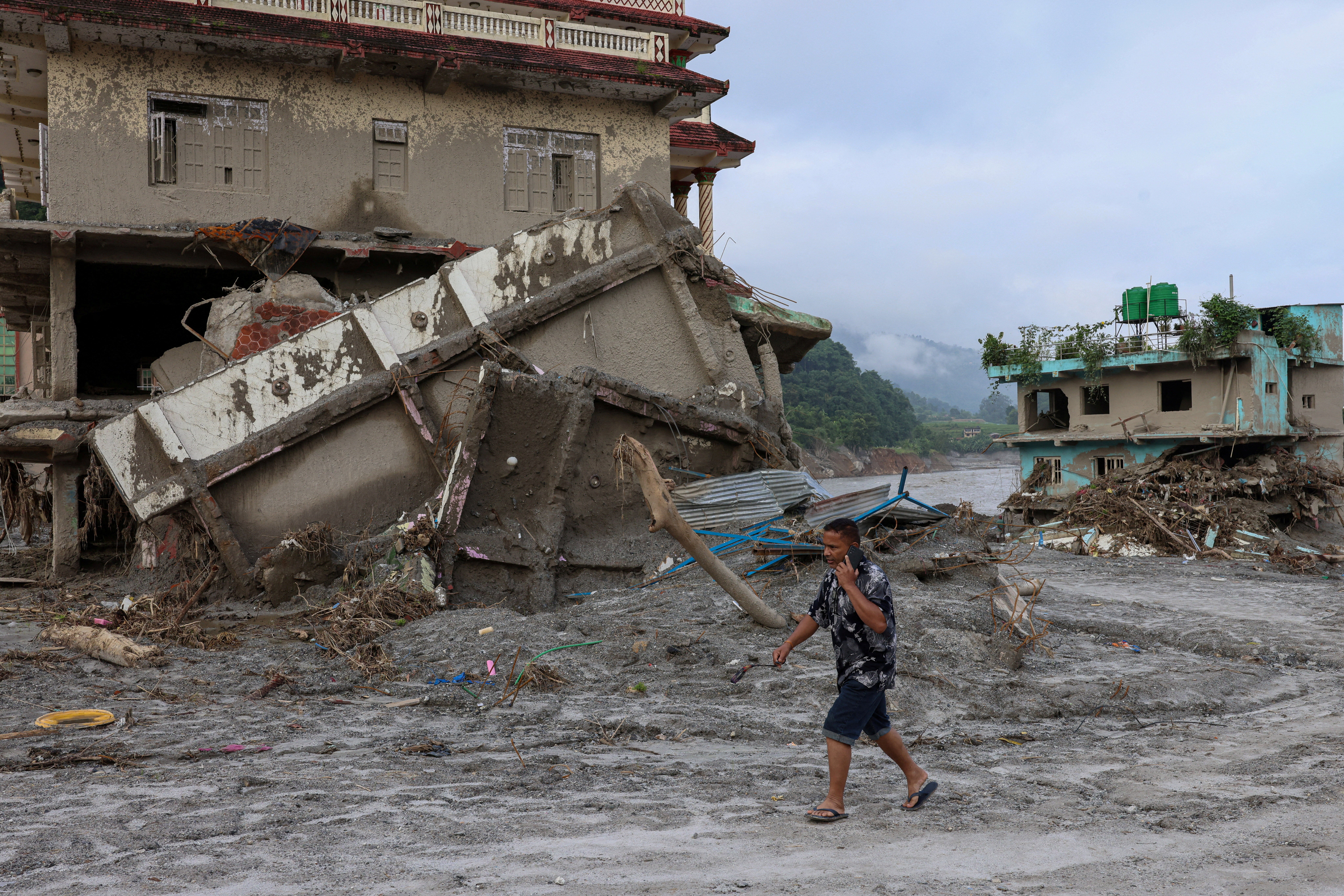 A man walks past damaged houses following deadly flash floods in Devighat, Nuwakot district, Nepal, on 8 September 2026
