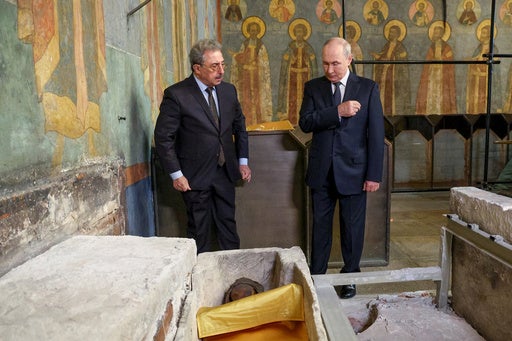 Russian President Vladimir Putin, right, crosses himself standing at the relics of the Holy Grand Prince Dmitry Donskoy, which were discovered during restoration works at the Archangel Cathedral of the Kremlin, in Mosсow, on Thursday, Aug. 20, 2026