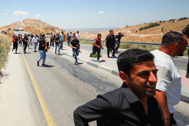 Palestinians run from tear gas smoke on a road in Jabal Tarousa near Dura, south of Hebron, in the occupied West Bank