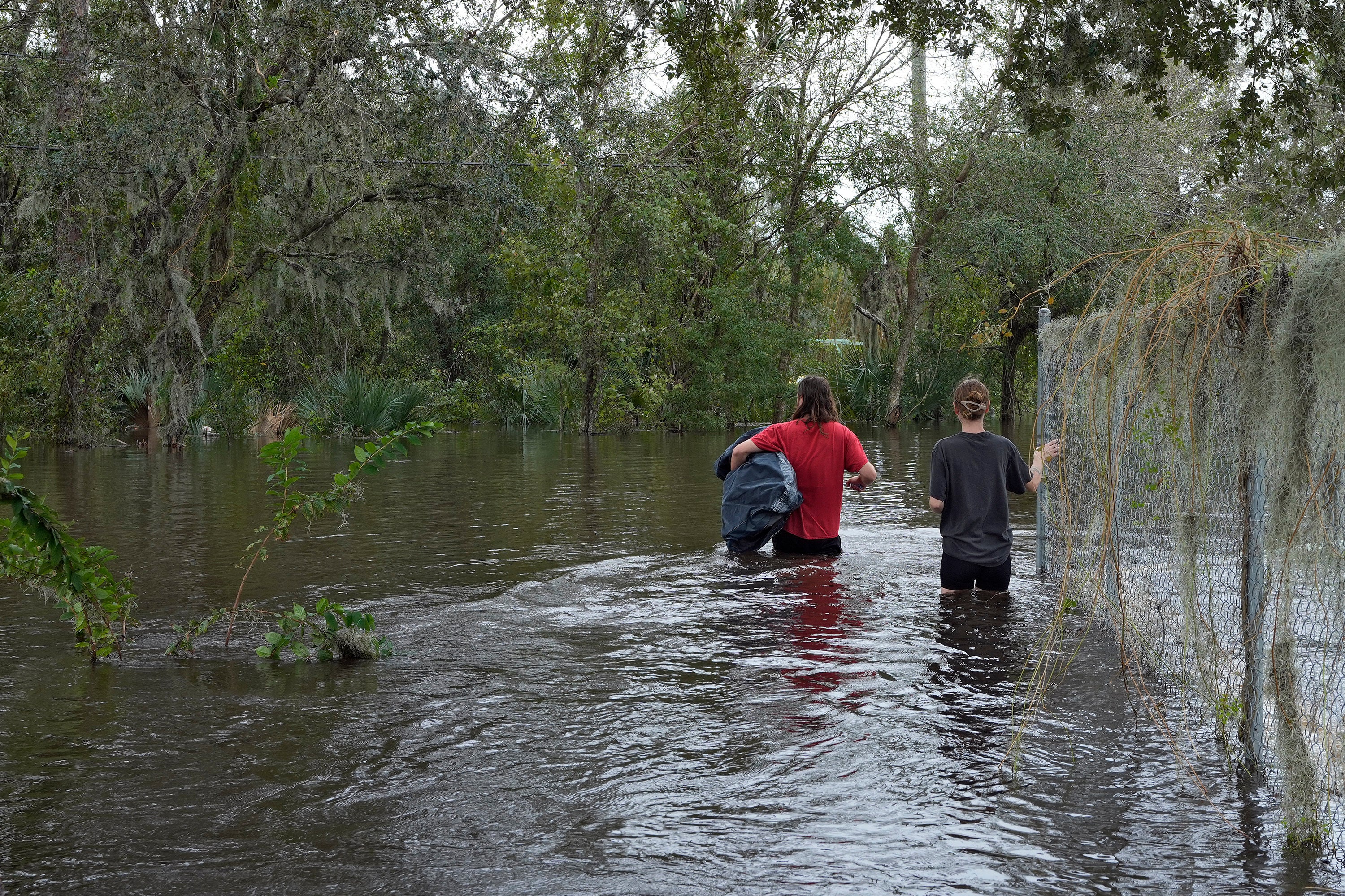 FILE - Connor Hughes and Kaylee Swenson walk through floodwaters from the Alafia River caused by Hurricane Milton, Oct. 11, 2024, in Lithia, Fla. (AP Photo/Chris O'Meara, File)
