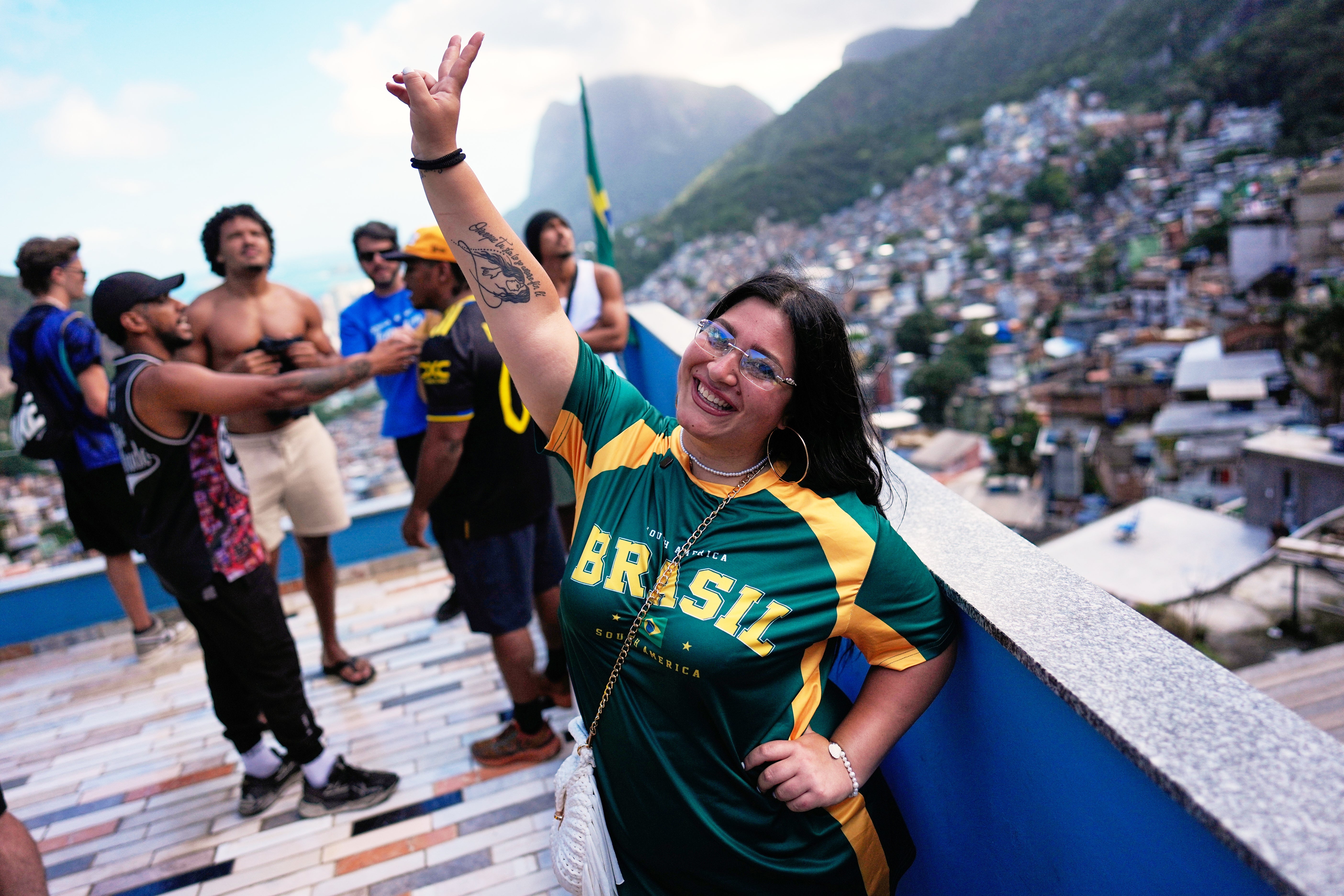 Italian tourist Edda Di Dato, wearing a Brazil's jersey, strikes a pose at a terrace in the Rocinha favela in Rio de Janeiro, on Sept. 2, 2026. (AP Photo/Silvia Izquierdo)