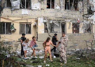 Residents leave a site of an apartment building damaged during a Russian drone strike
