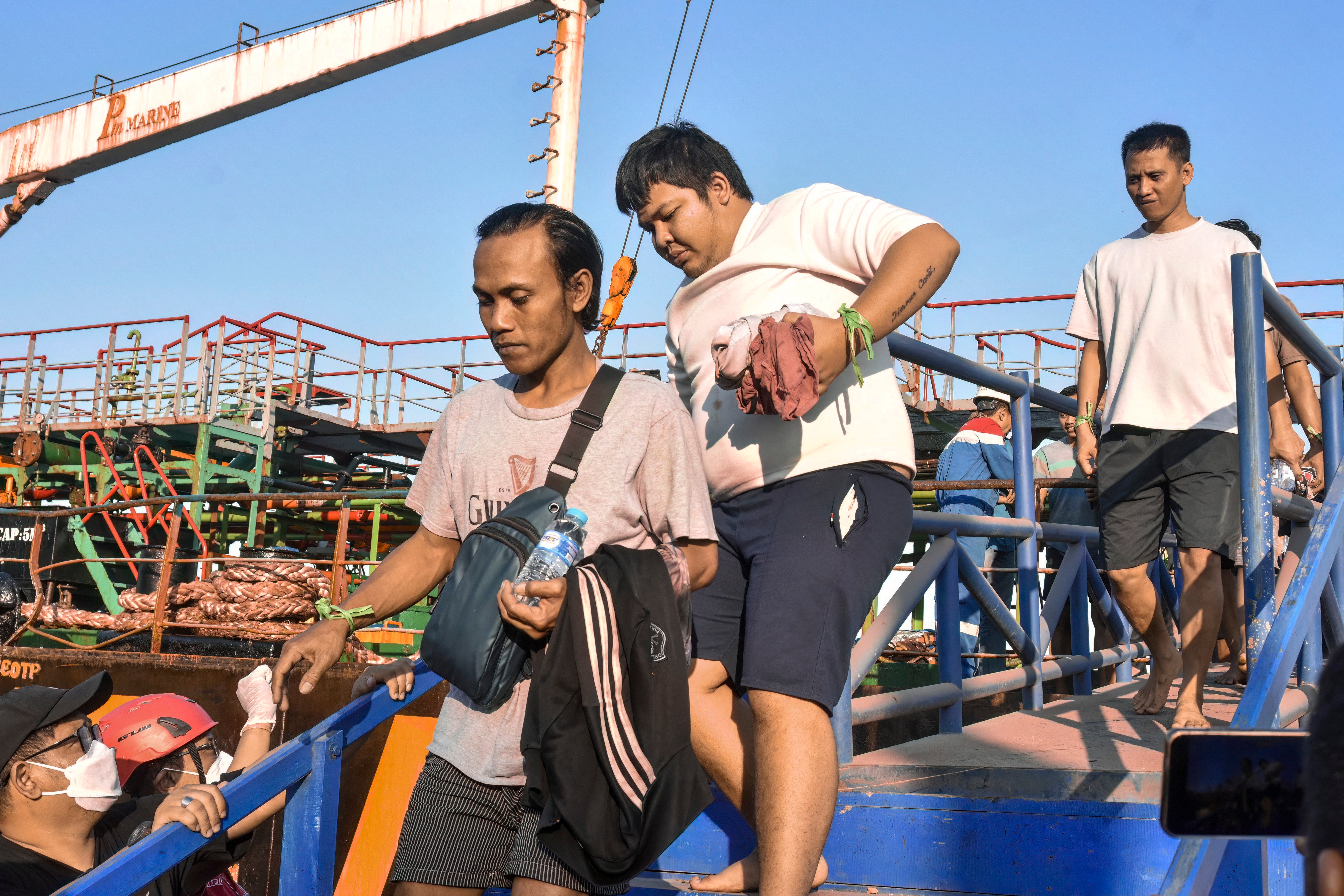 Survivors of the Virgo Transport 8 passenger ferry, which capsized 13 September carrying 213 passengers and 30 crew while en route from Banjarmasin to Surabaya, disembark following their rescue at the port in Banjarmasin, South Kalimantan, on 14 September 2026