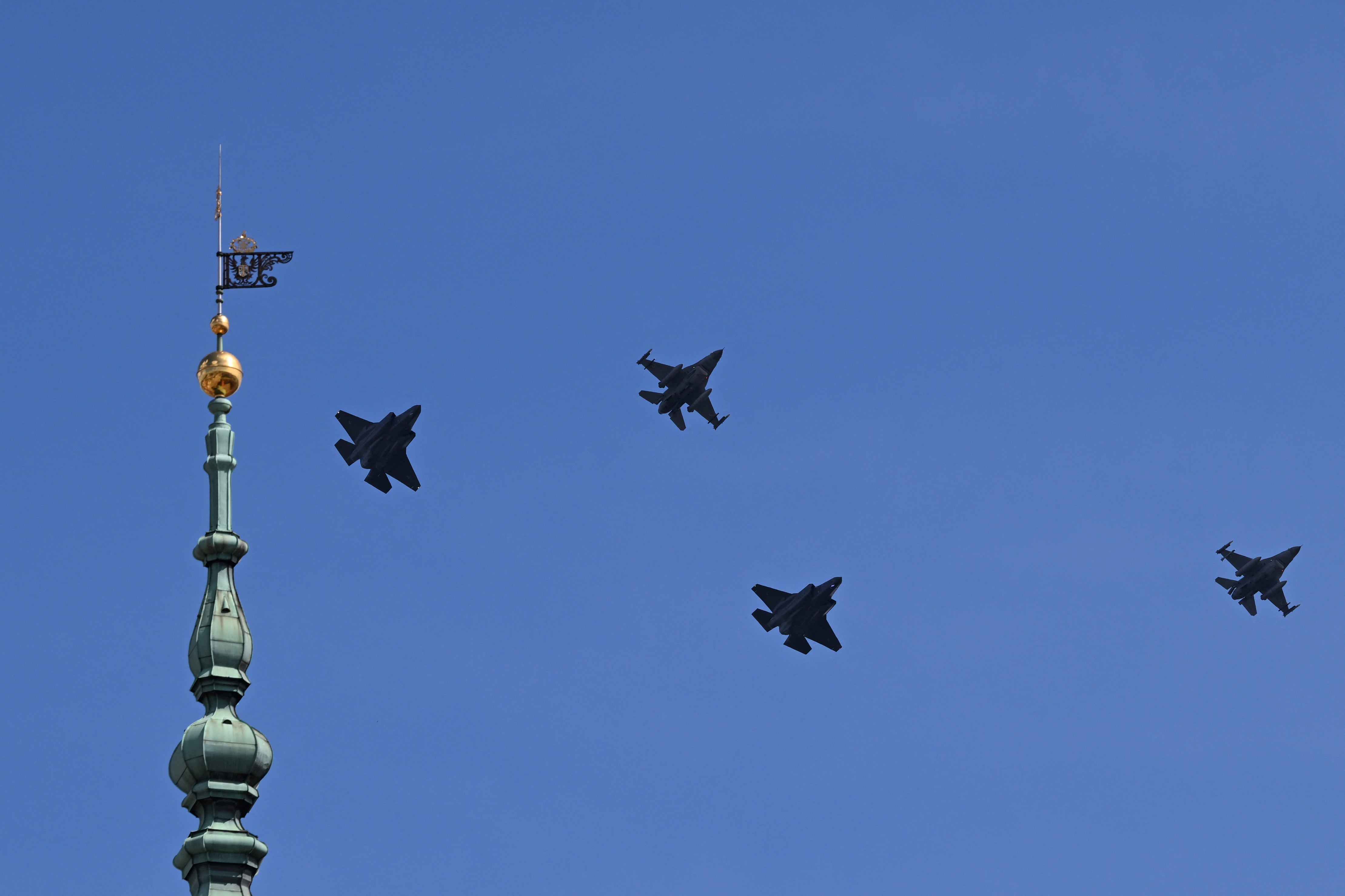 Two US-made F-35 (L and 2nd R) and two F-16 fighter jets fly past the top of the clock tower (L) of the Royal Castle in Warsaw on June 12, 2026, during a ceremonial flyover across Poland welcoming the first F-35 aircraft into service with the Polish Air Force.