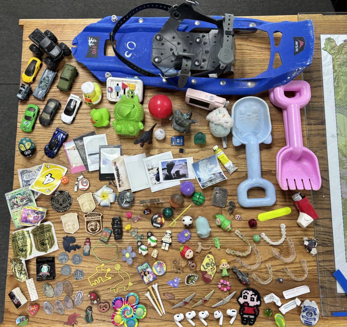 A selection of random trash that the Yellowstone National Park geology group removed during a hydrothermal area clean-up. The items include AirPods, airline flight pins, mini-Polaroid images, and five Invisalign retainers