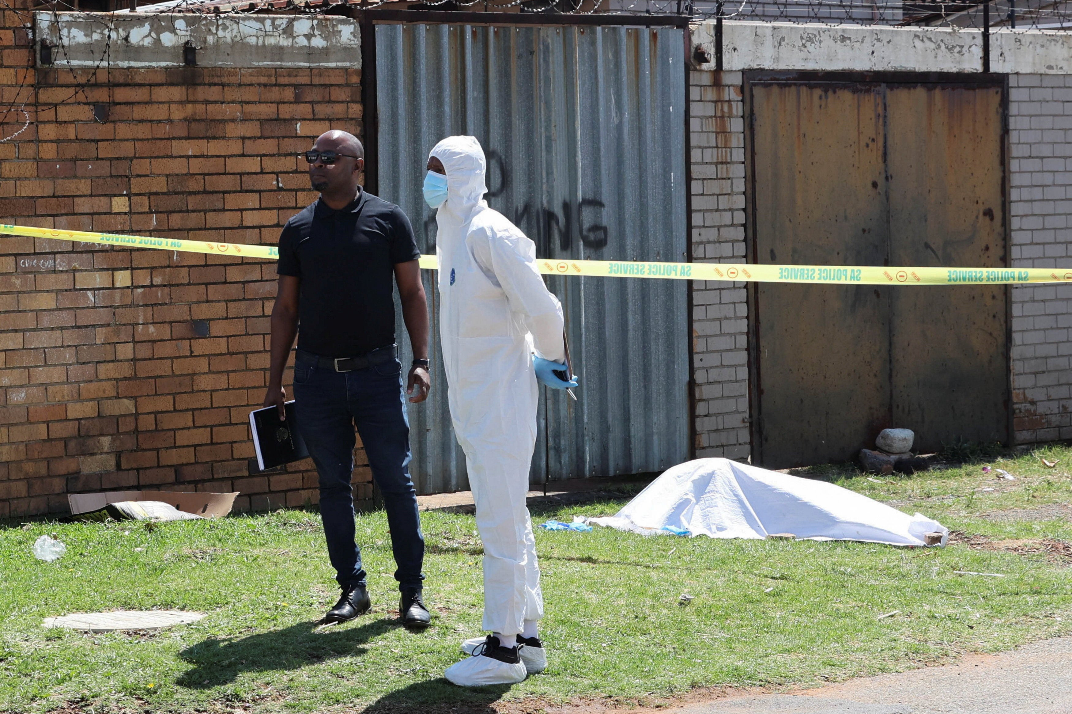 People stand near a cordoned-off crime scene where the body of one of seven women killed was found in Ekurhuleni, east of Johannesburg, South Africa, September 15, 2026