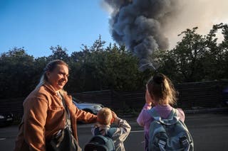A woman and children stand near a site of a Russian drone strike as smoke rises from there, amid Russia’s attack on Ukraine, in Kyiv, Ukraine September 16, 2026.
