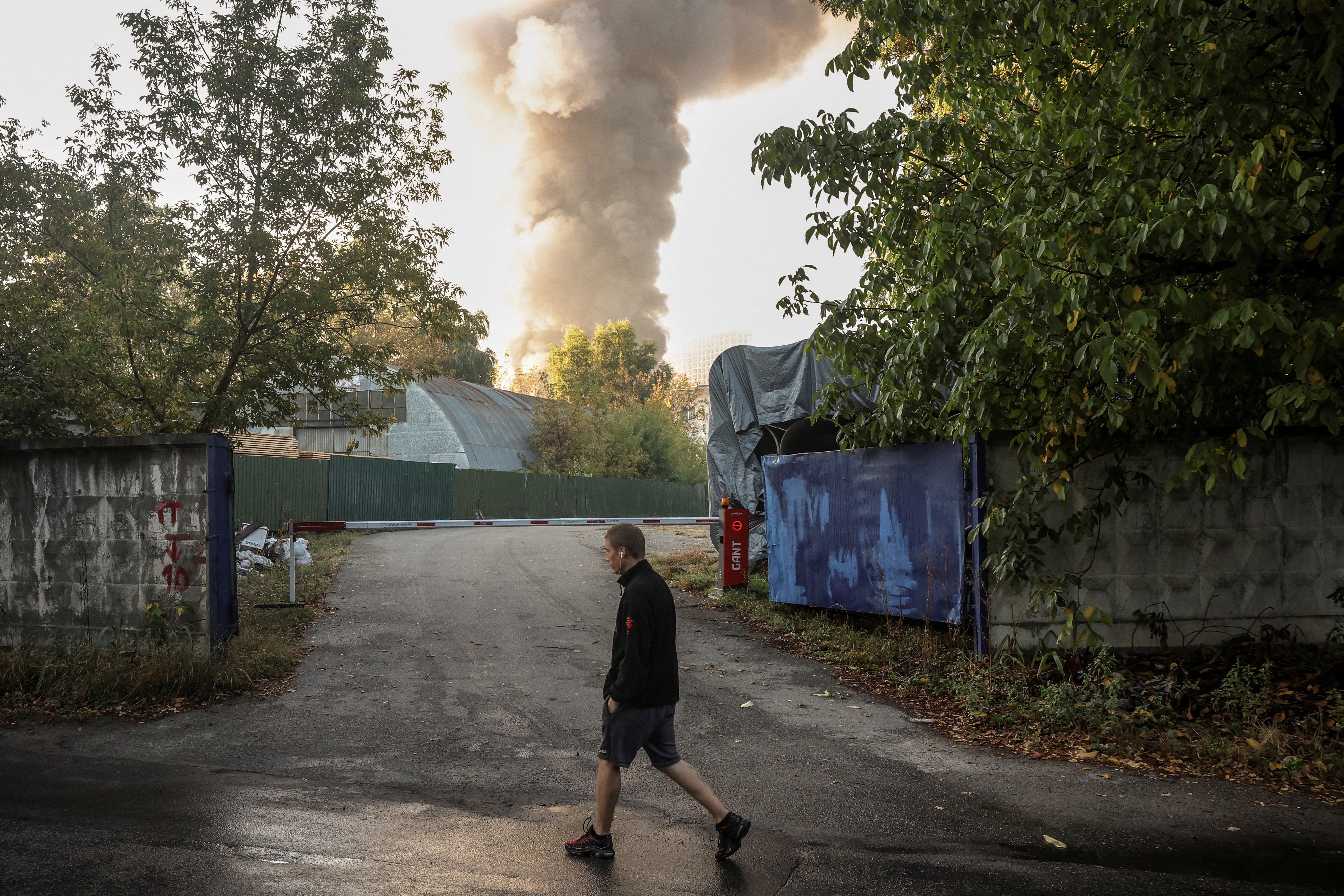 A person passes by the site of a Russian drone strike as smoke rises in the background, amid Russia’s attack on Ukraine, in Kyiv, Ukraine, September 16, 2026. (Reuters)