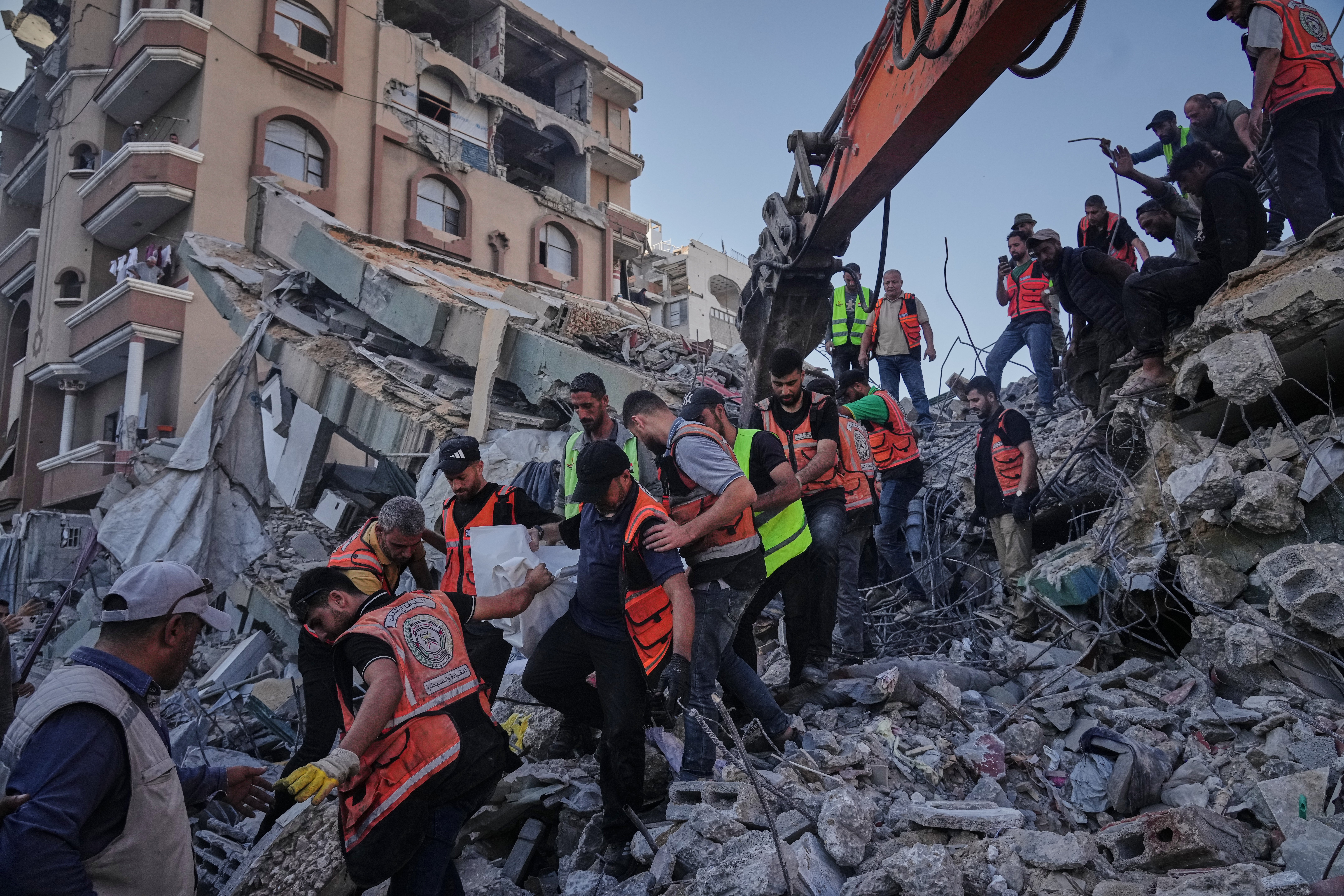 Crews carry a body from the rubble of the collapsed building