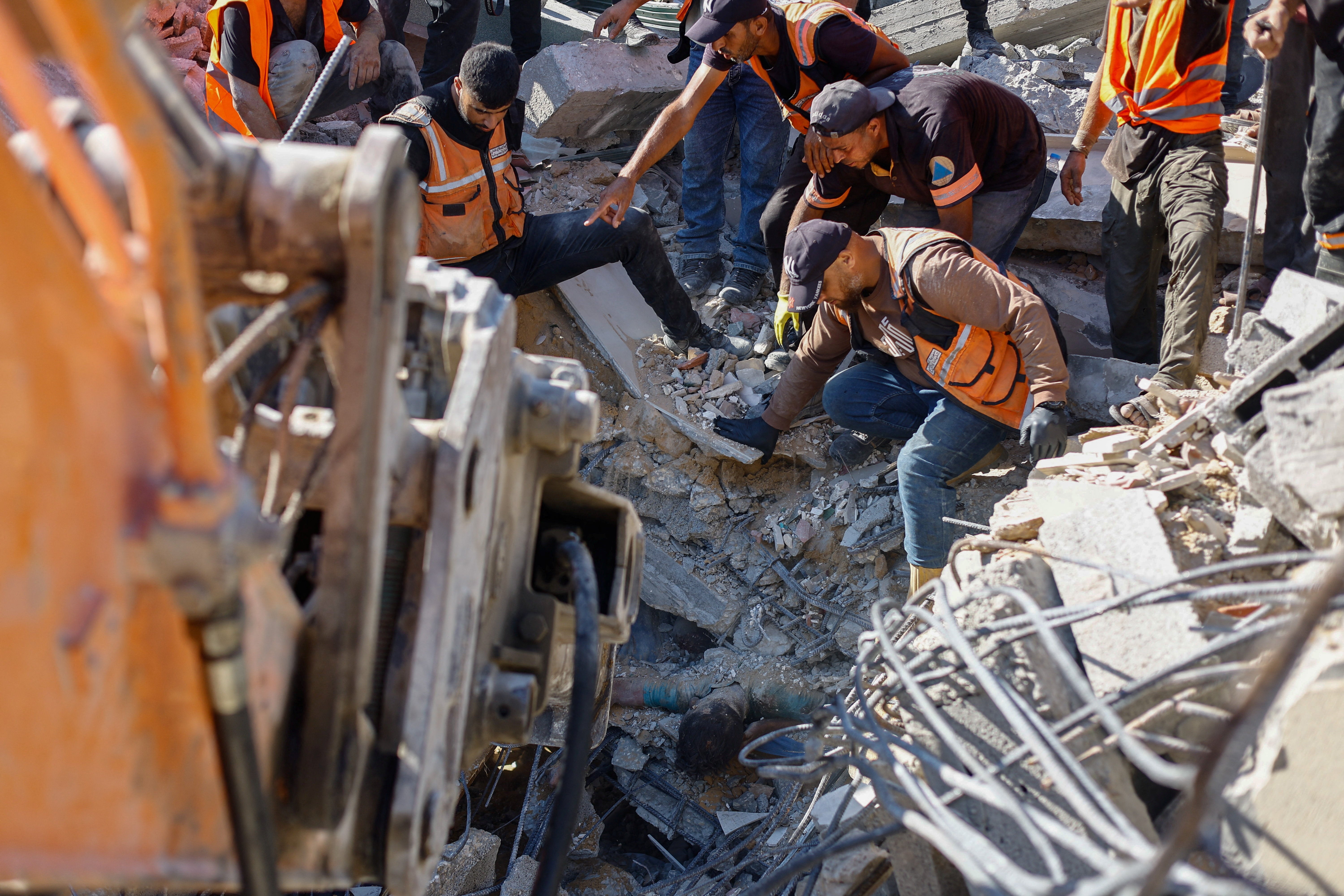 Rescuers work to recover the body of a Palestinian from under the rubble of a residential building that had been damaged in an earlier Israeli strike