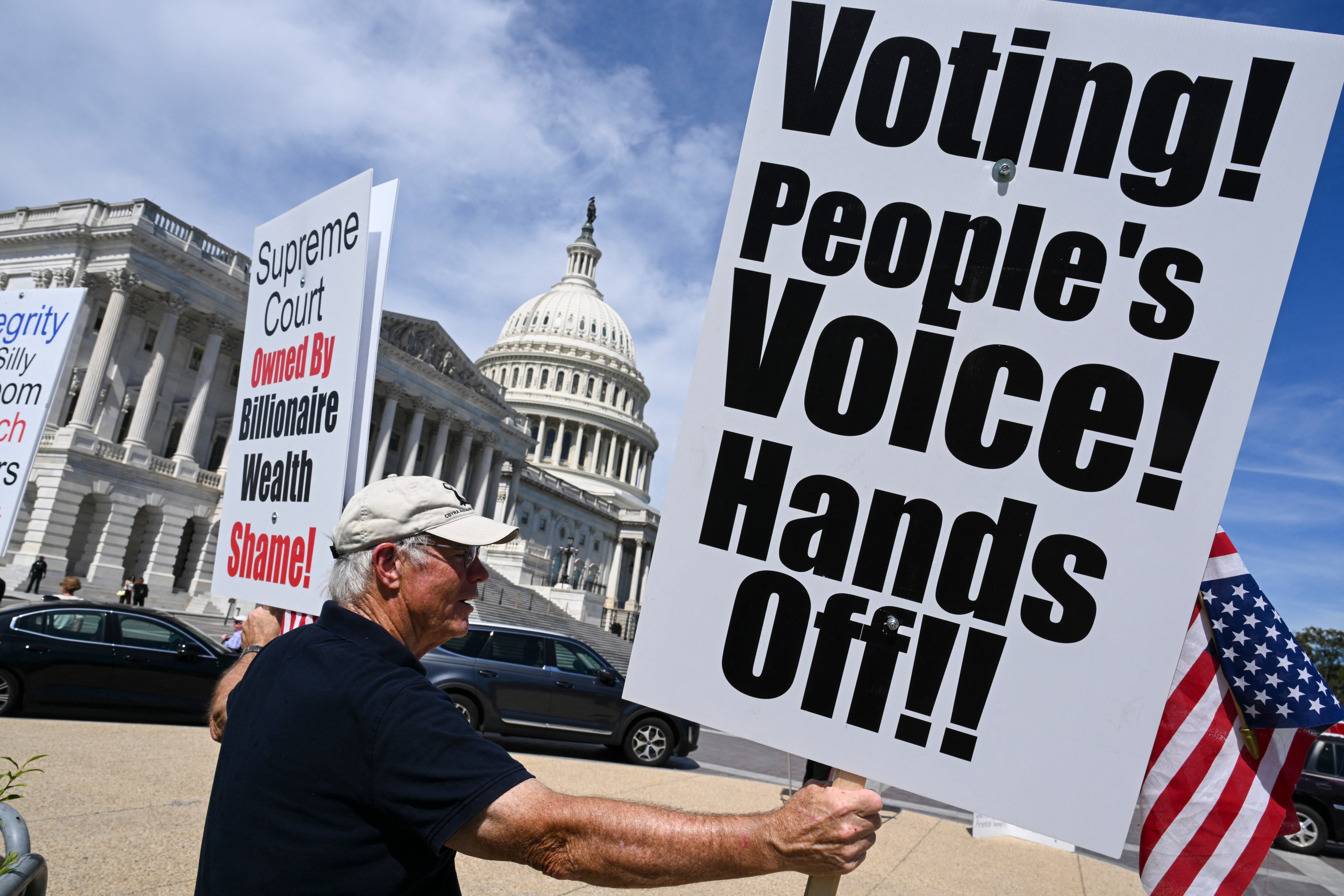 Demonstrators hold signs as they protest against US President Donald Trump's executive order that aimed to change how Americans vote by mail