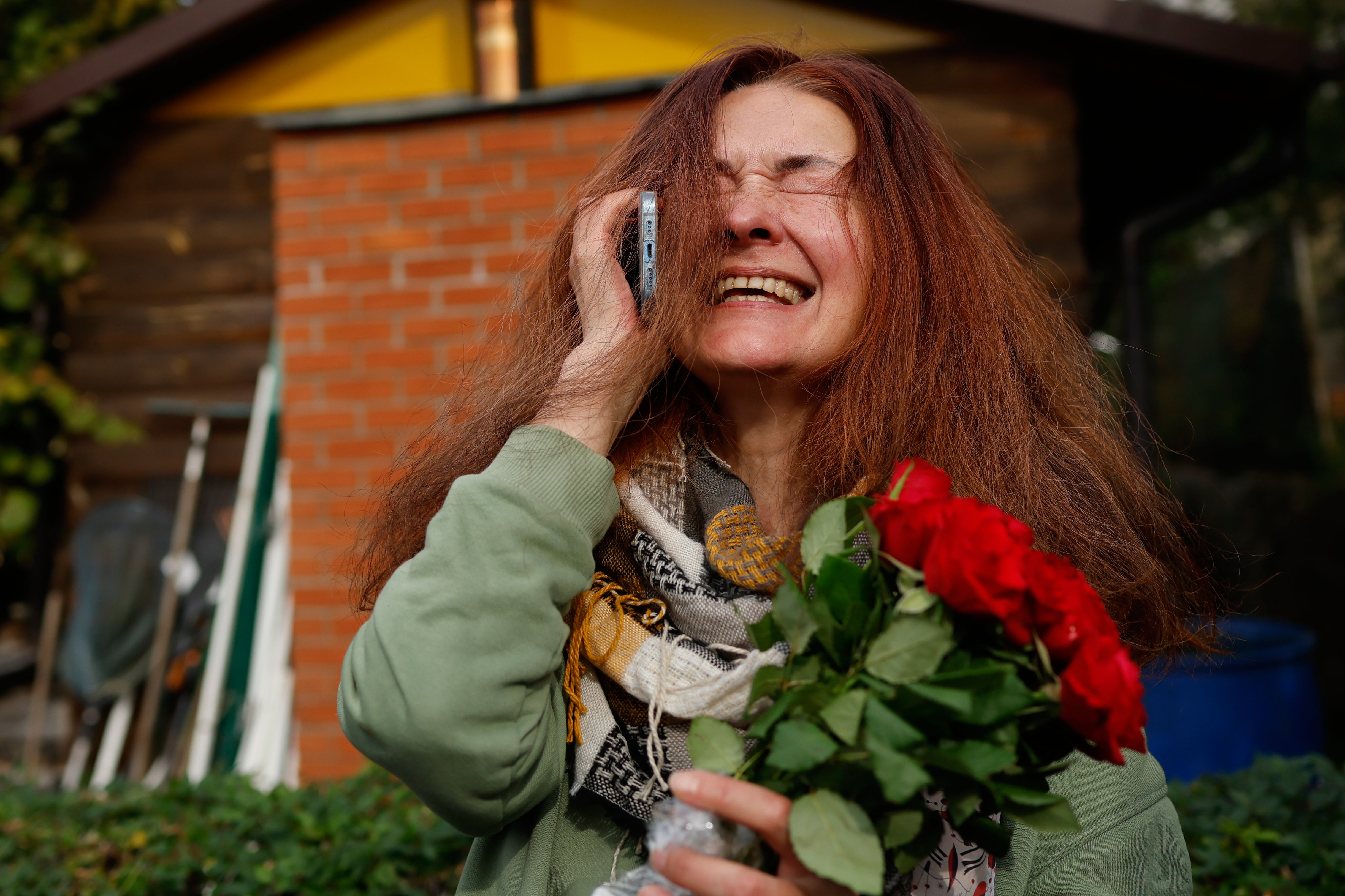 Tatsiana Kouzina, one of the released Belarusian prisoners reacts as she speaks on the phone upon her arrival in Vilnius, Lithuania (AP)