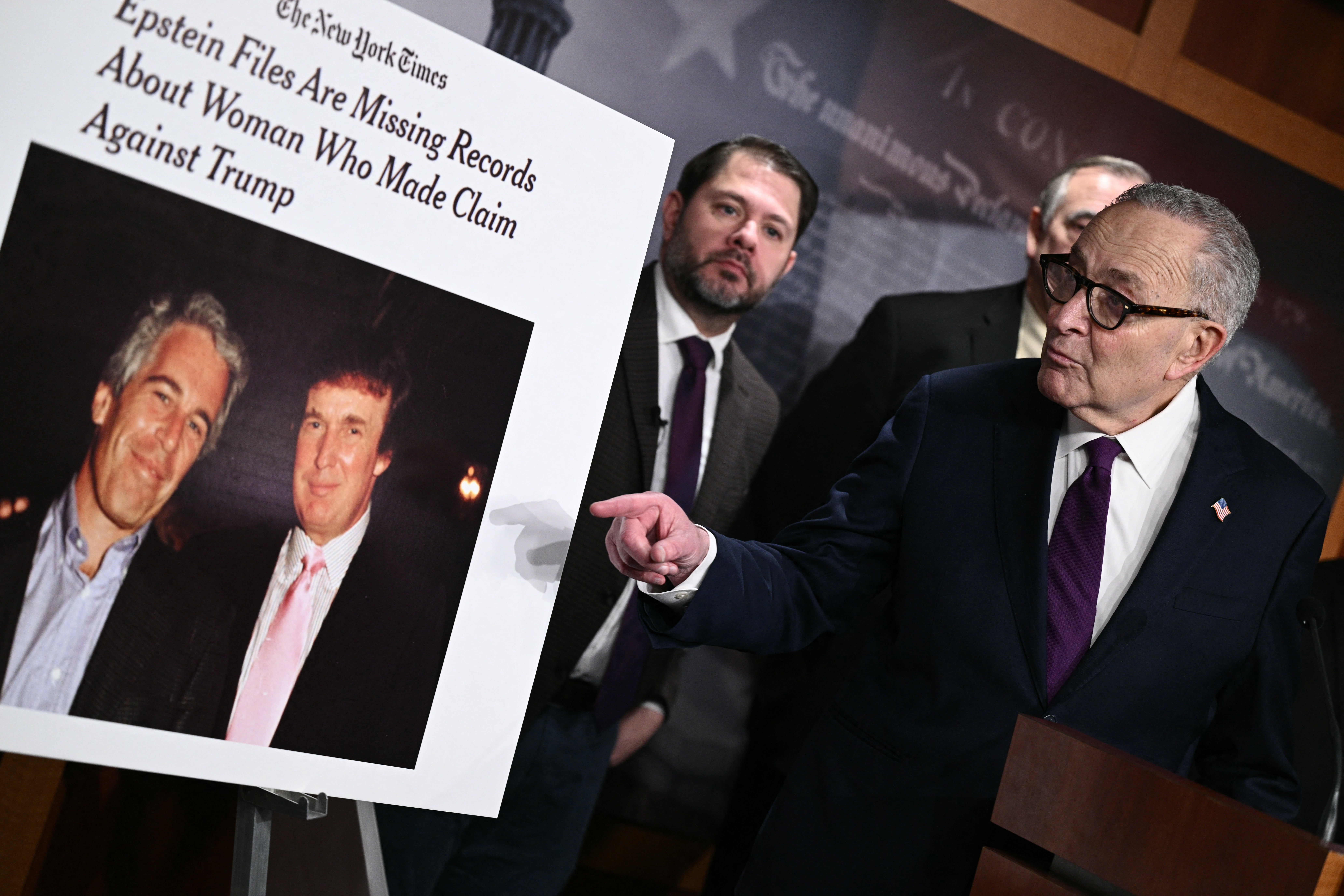A sign showing a photo of President Donald Trump and Jeffrey Epstein is displayed by Senate Minority Leader Chuck Schumer during a press conference to announce oversight efforts on the files of convicted sex offender Epstein on February 26, 2026 (AFP/Getty)