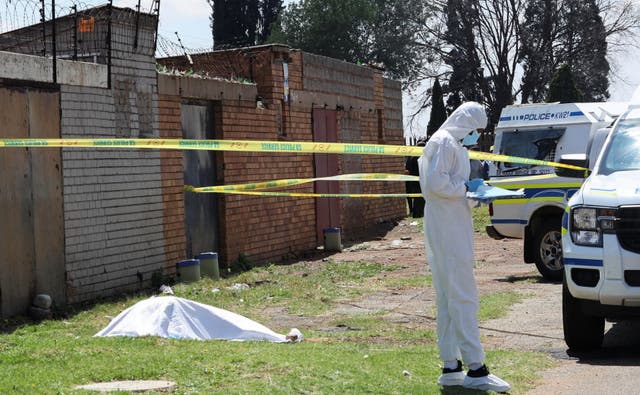 A forensic investigator works near a cordoned-off crime scene in Ekurhuleni, east of Johannesburg