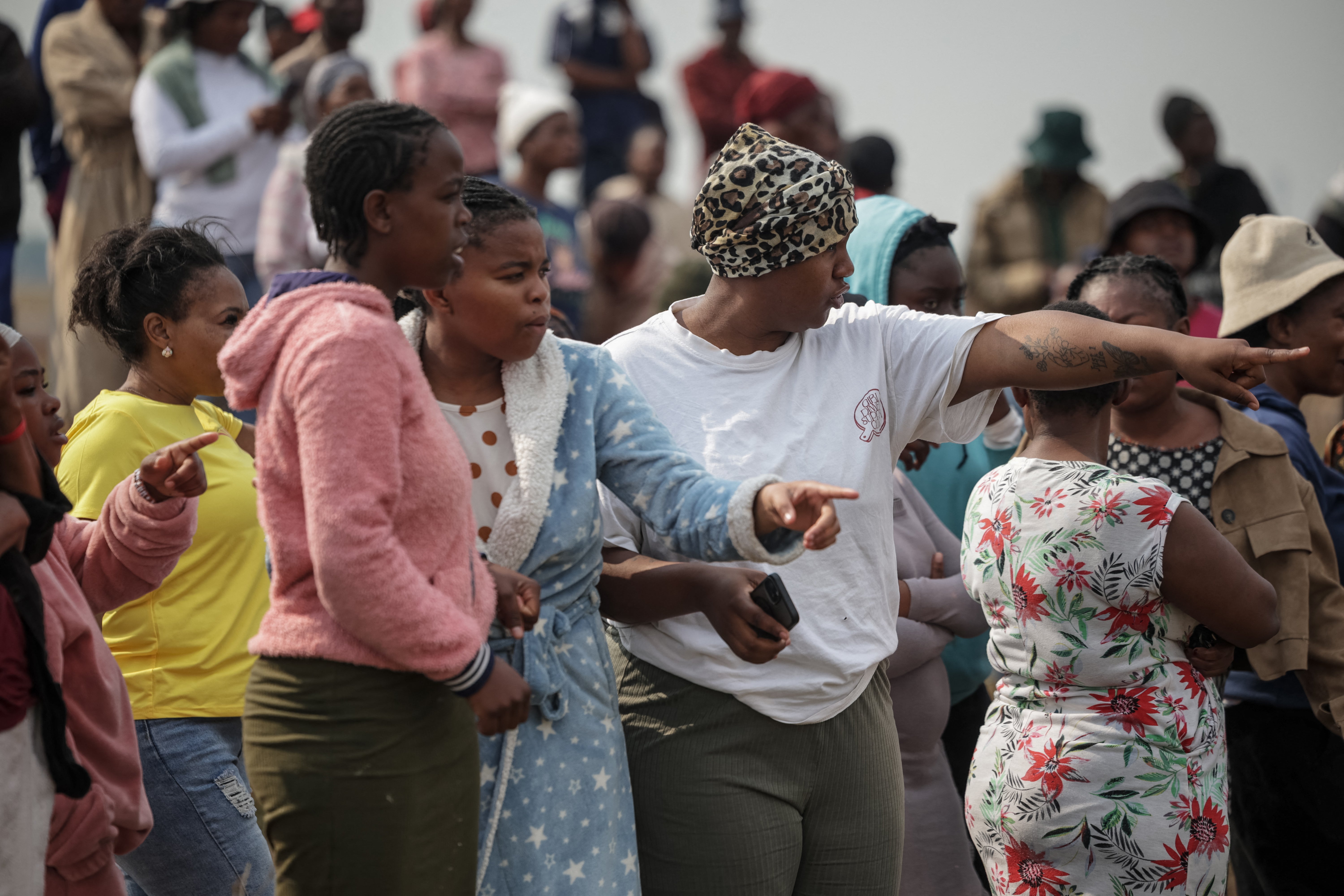 People gather and point in the direction of the crime scene where the body of a woman was discovered in Boksburg on September 17, 2026.