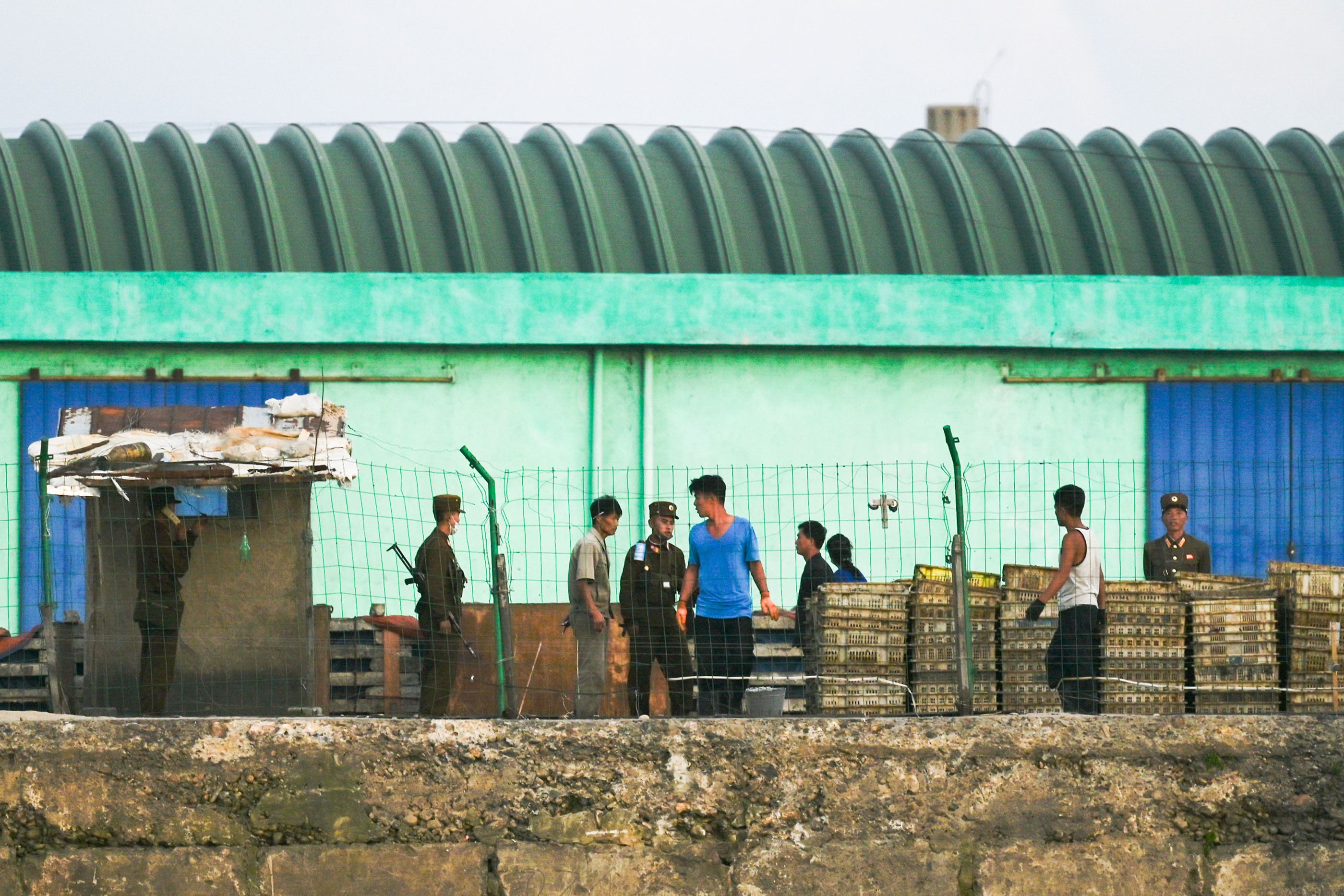Soldiers and civilians working on a dock in the North Korean town of Sinuiju as seen from China (AFP/Getty)