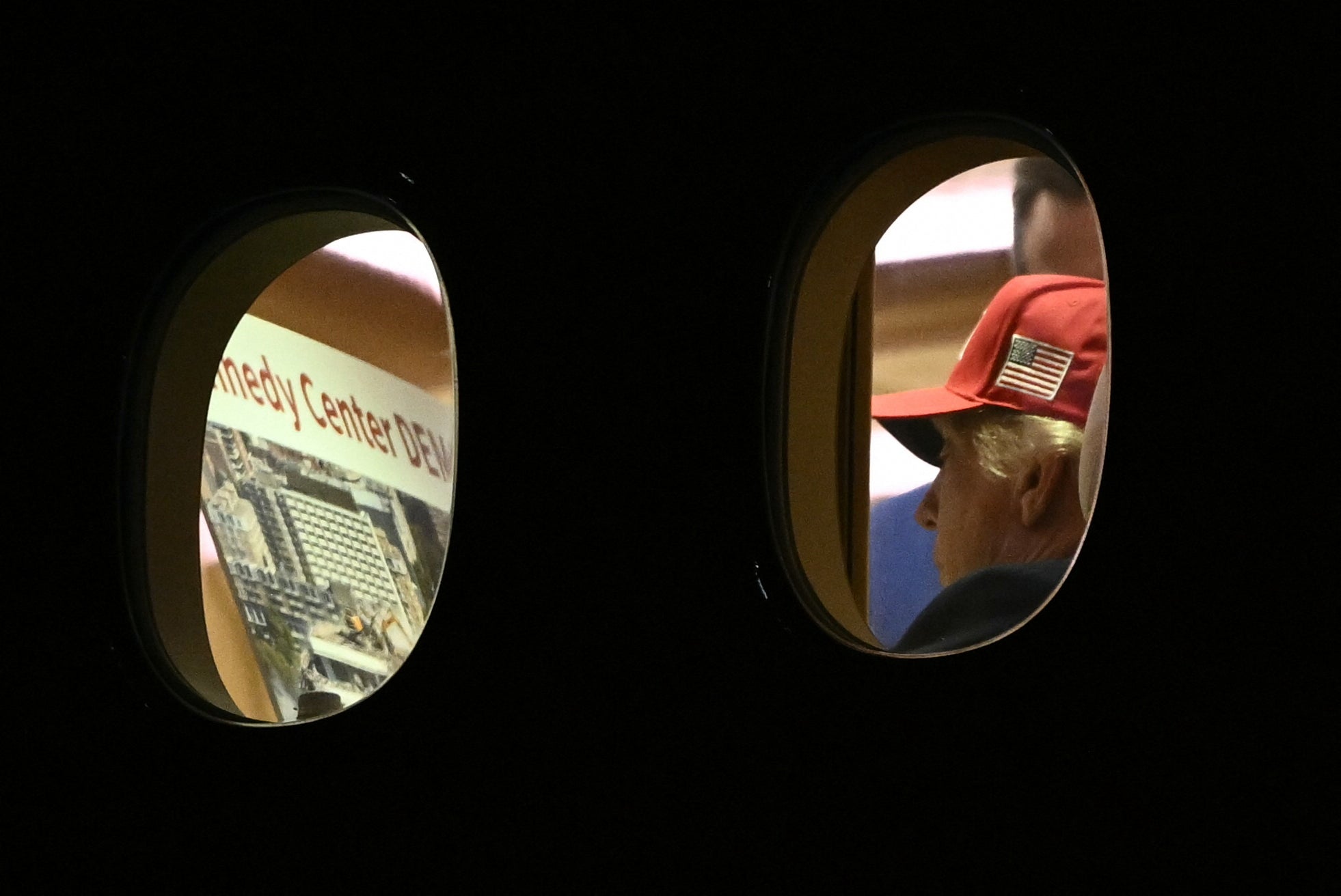 President Donald Trump seen through the window of Air Force One Wednesday appearing to peruse a booklet outlining the potential demolition of the Kennedy Center in Washington, D.C.