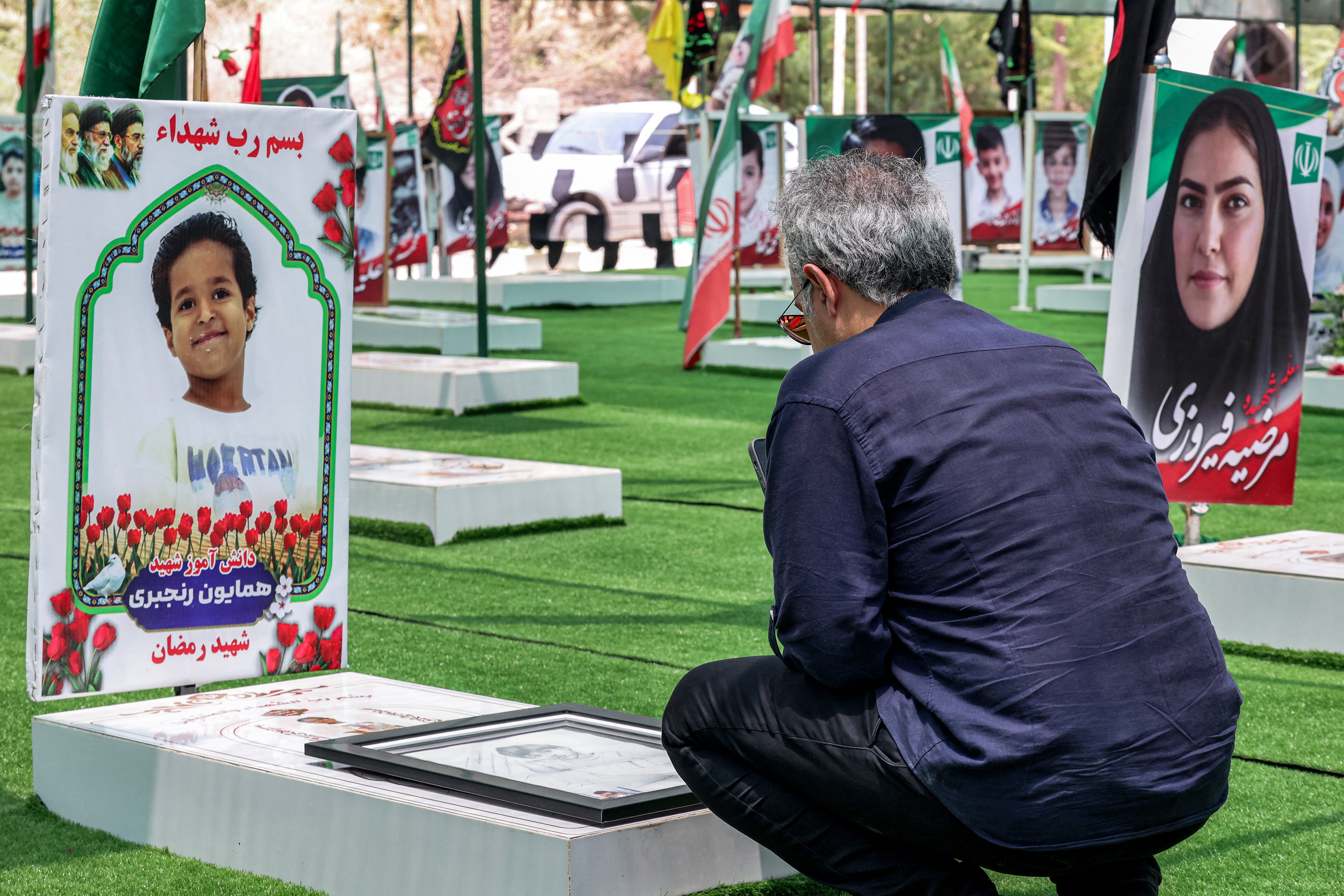 A man visits one of the graves of people and children killed during the strike on the primary school