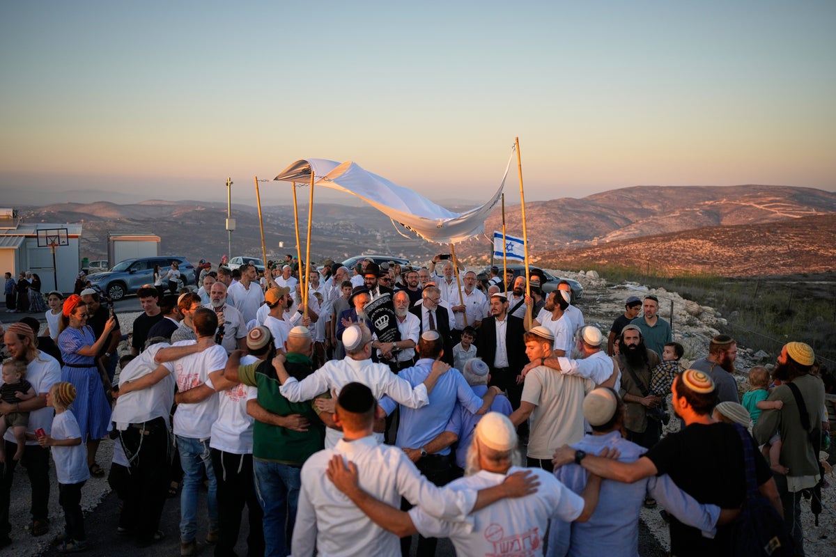 Israeli settlers, some armed, celebrate a new synagogue in the occupied West Bank, in photos