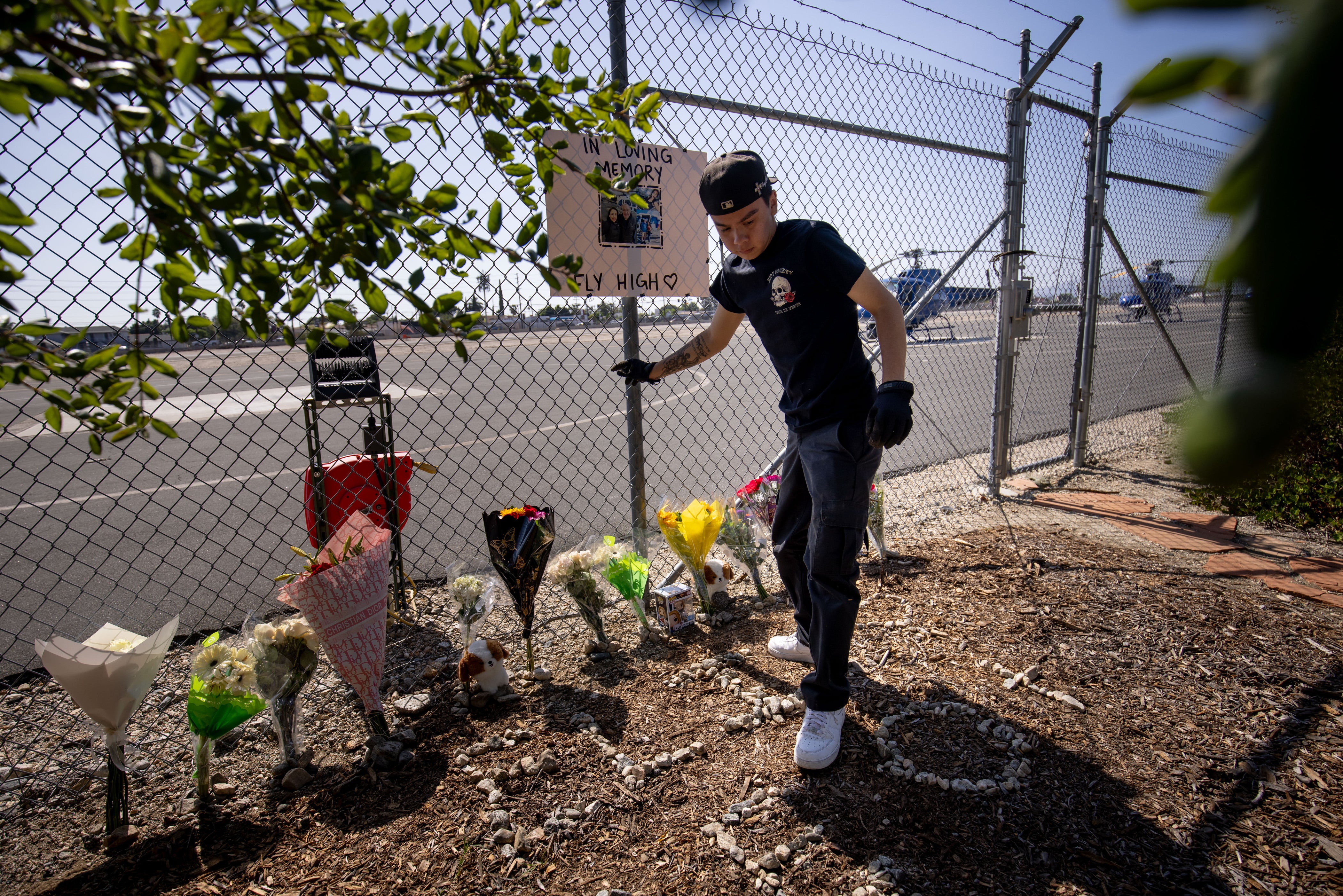 A person adjusts flowers at a memorial for Eliana Moreno and George Marciniw