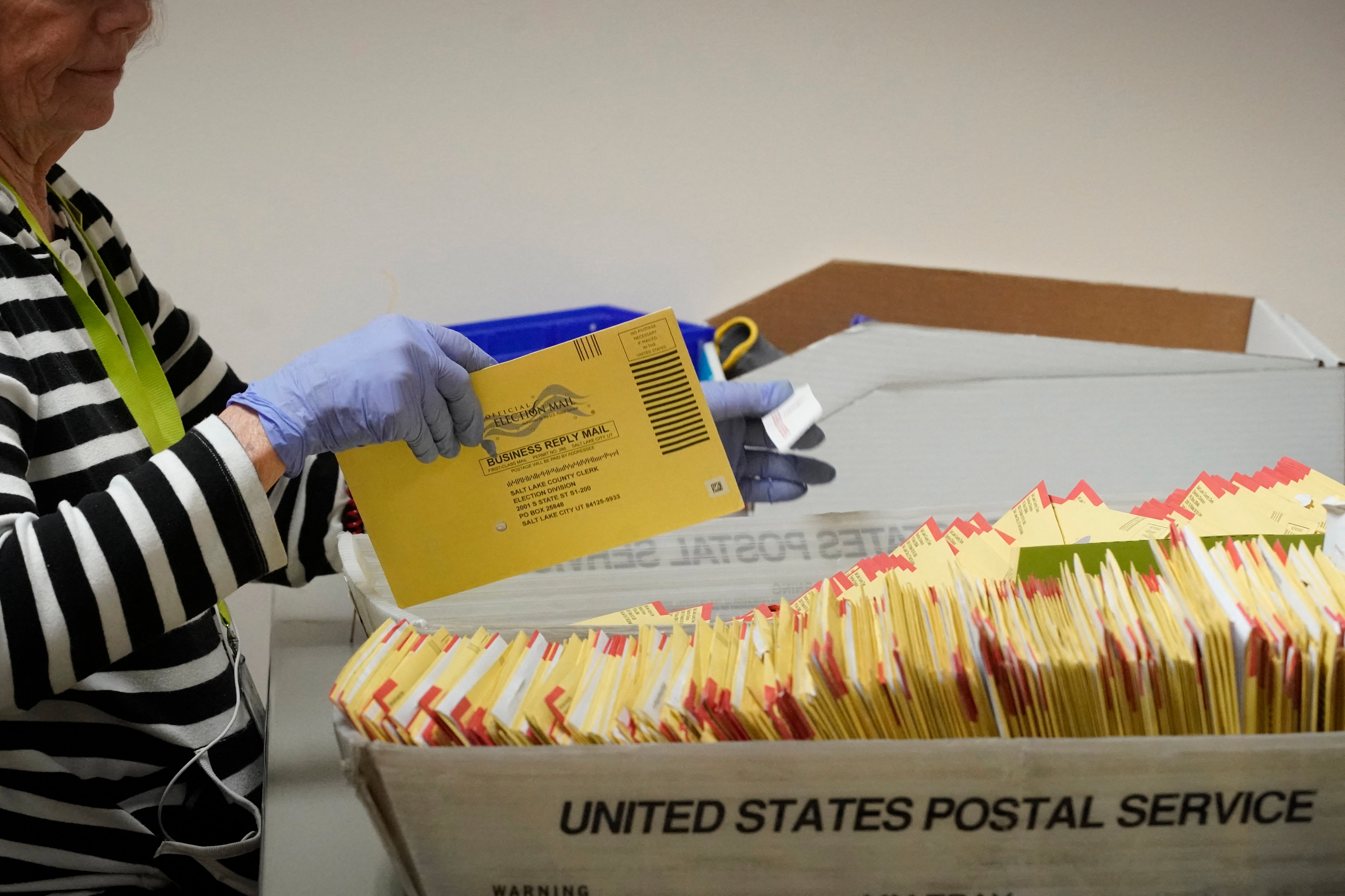 An election worker processes a container of mail-in ballots from the postal service to be processed at the Salt Lake County election offices in Salt Lake City