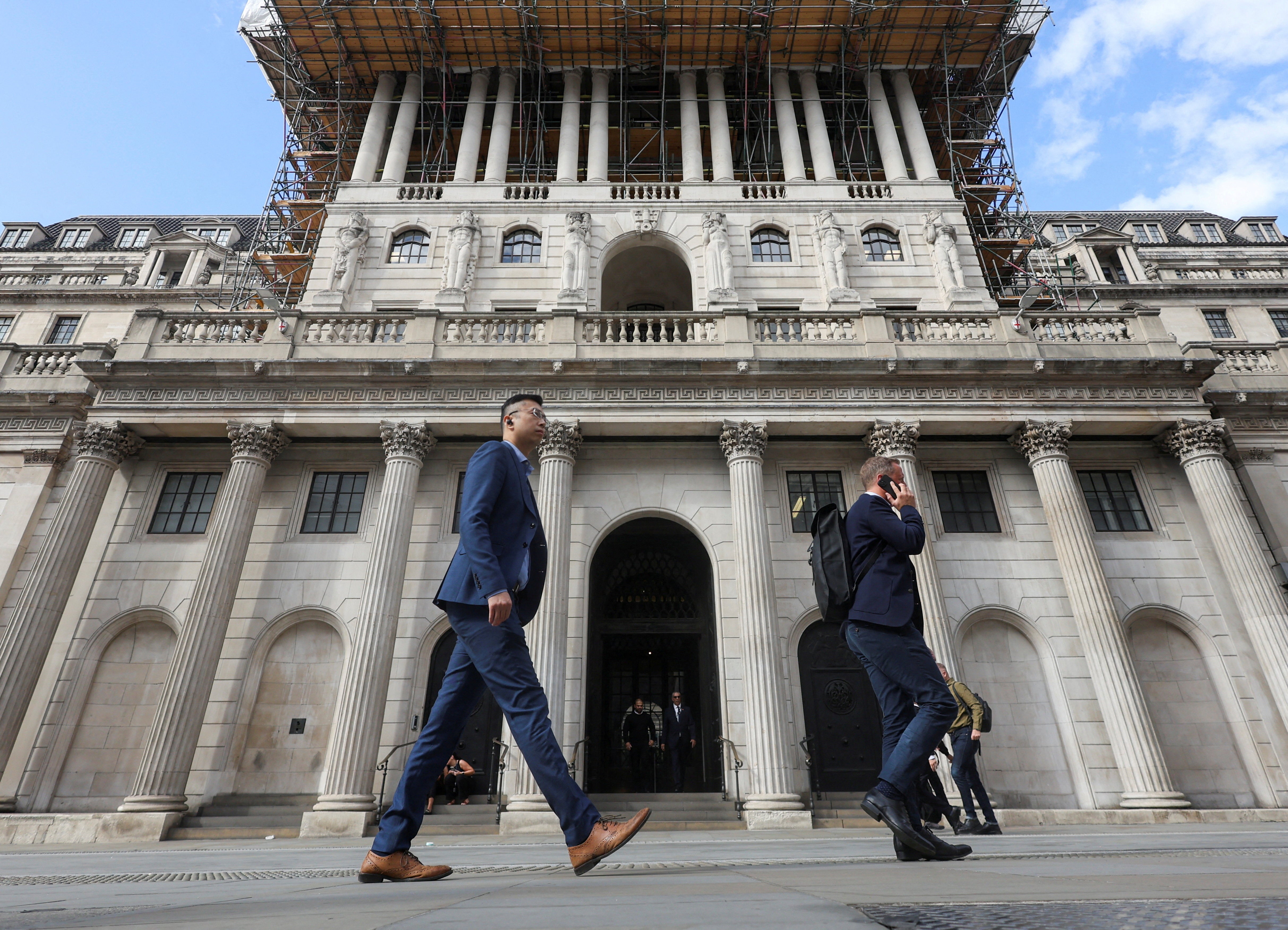 People walk past the Bank of England building in London