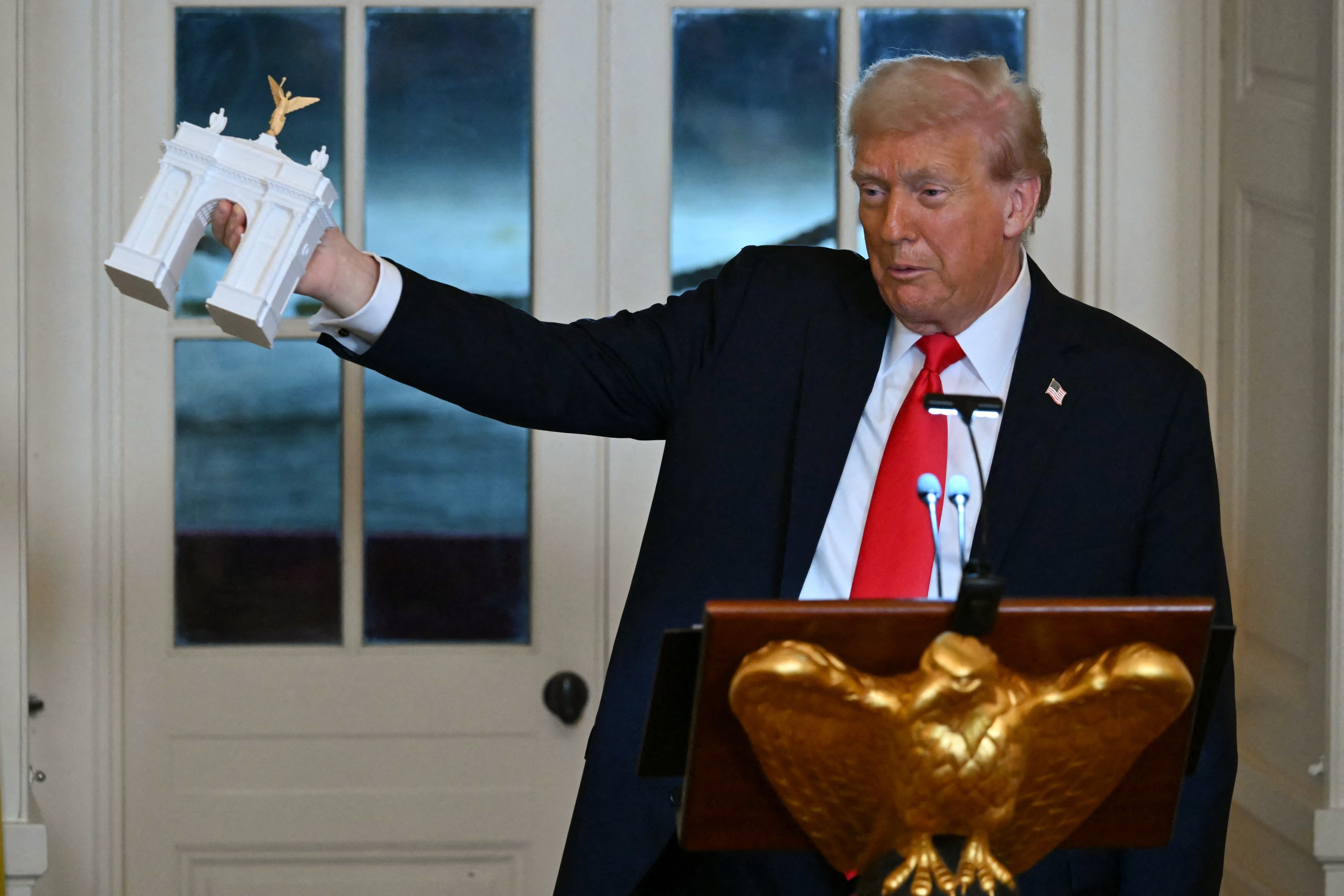 Trump holds up a model of the proposed arch during a dinner with ballroom donors in the East Room of the White House on Oct. 15, 2025