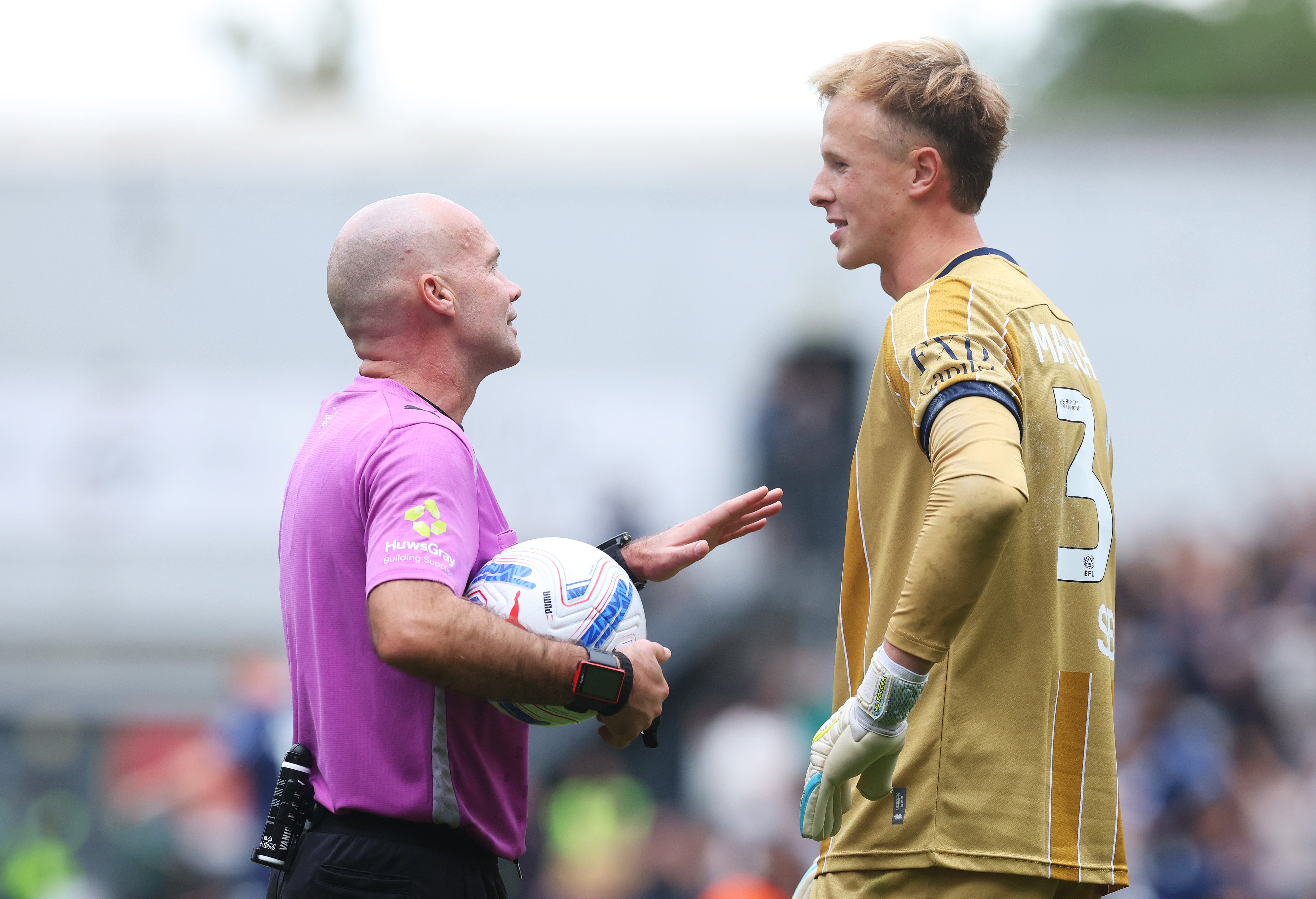 Millwall goalkeeper Filip Marschall speaks with referee Paul Tierney during the match against West Ham