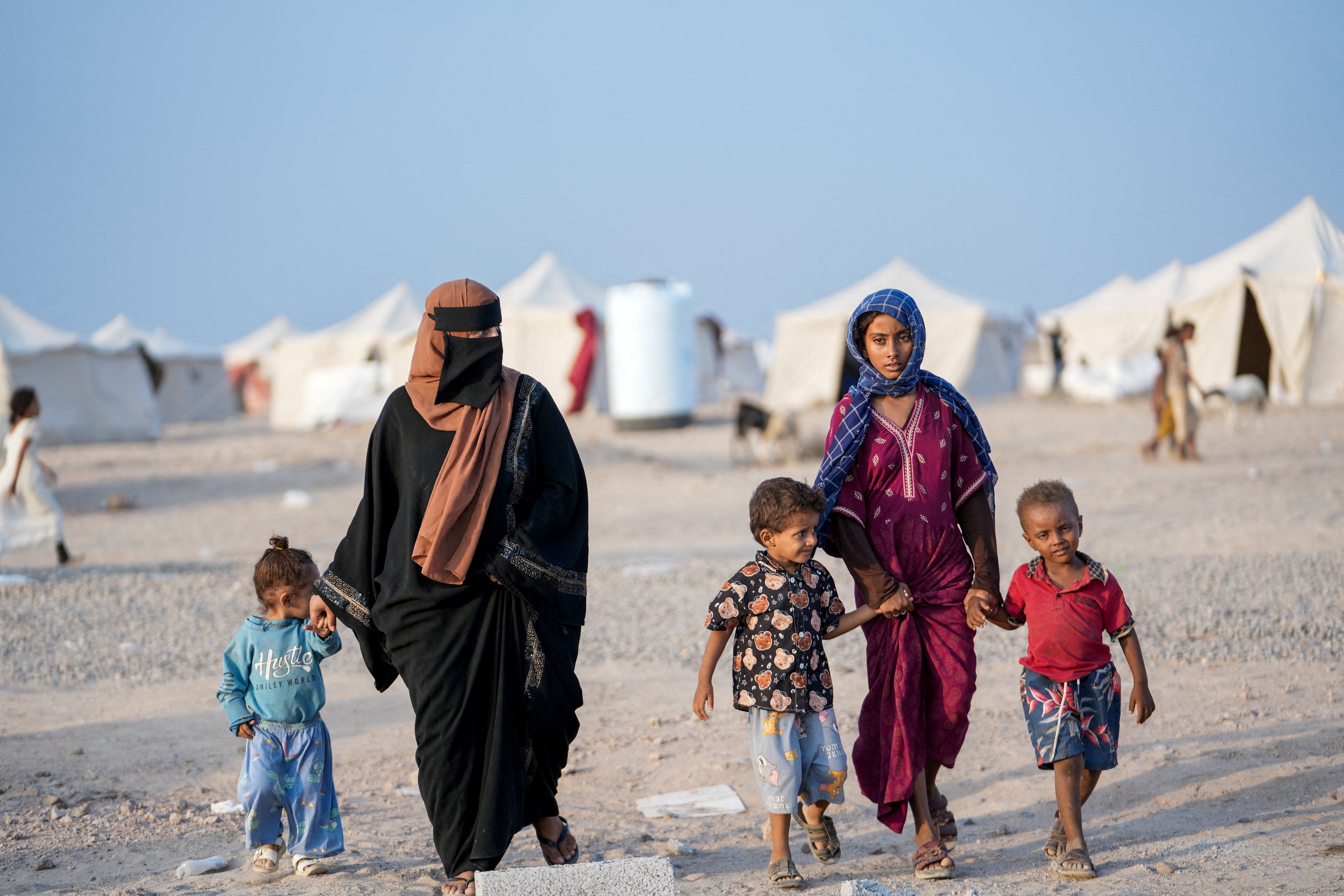 Women and children, who fled fighting between the Houthis and government forces in Red Sea coastline areas, walk at a camp for internally displaced people near Aden, Yemen