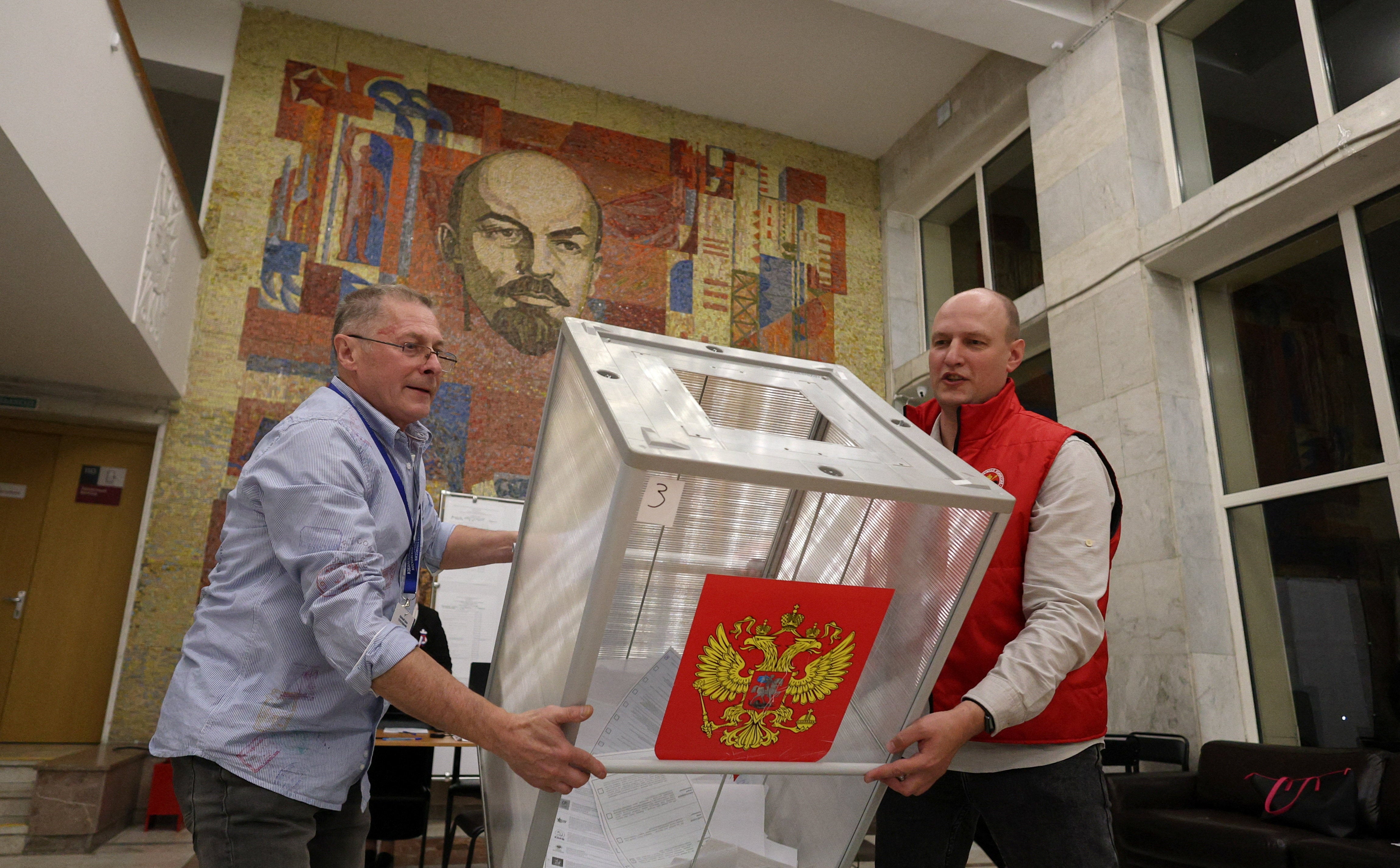 Members of a local electoral commission empty a ballot box before counting votes after the closure of a polling station
