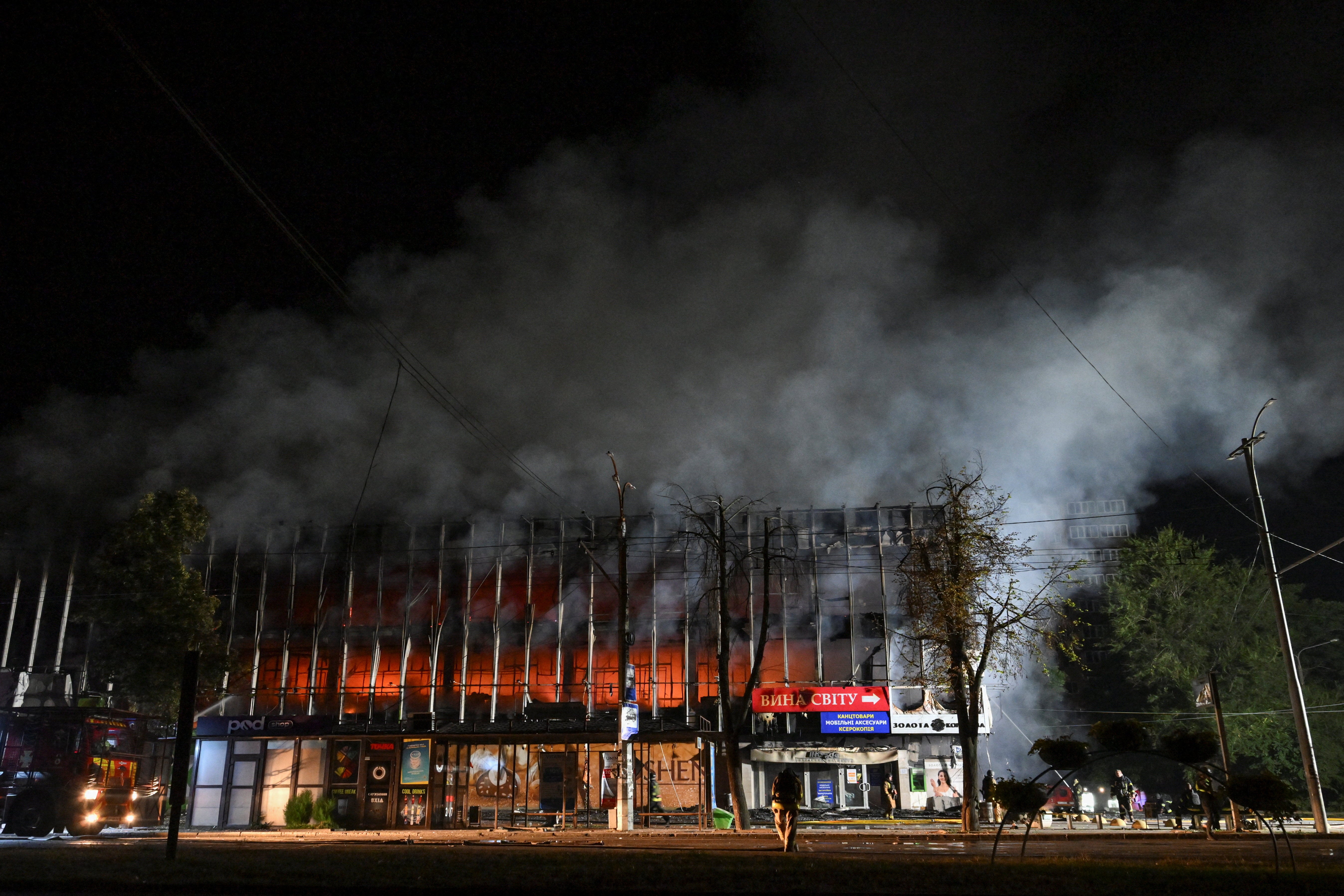 Firefighters work at the site of a shopping mall hit by an overnight Russian drone strike