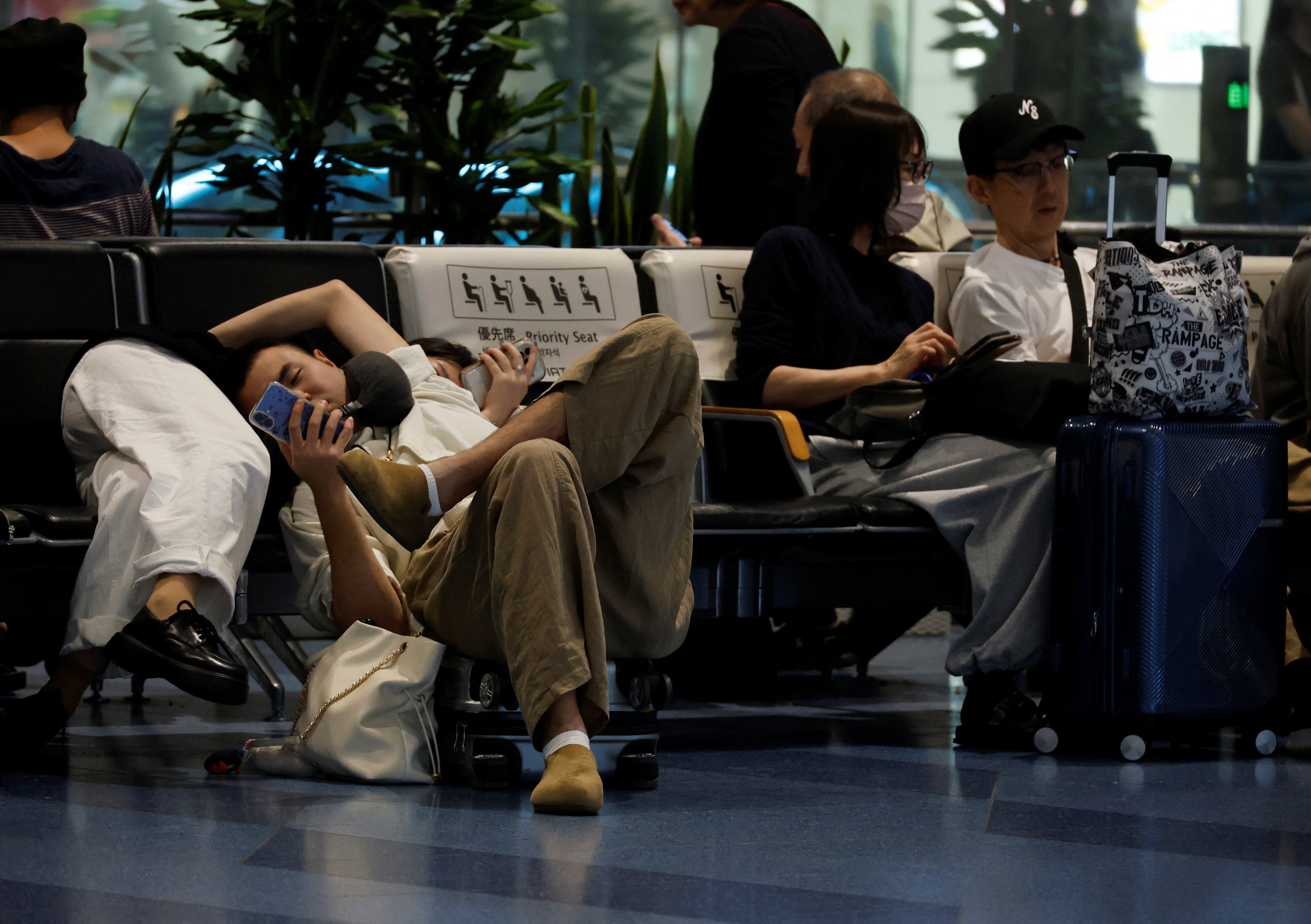 Passengers rest at the Haneda airport as many flights are delayed and cancelled due to Typhoon Dujuan