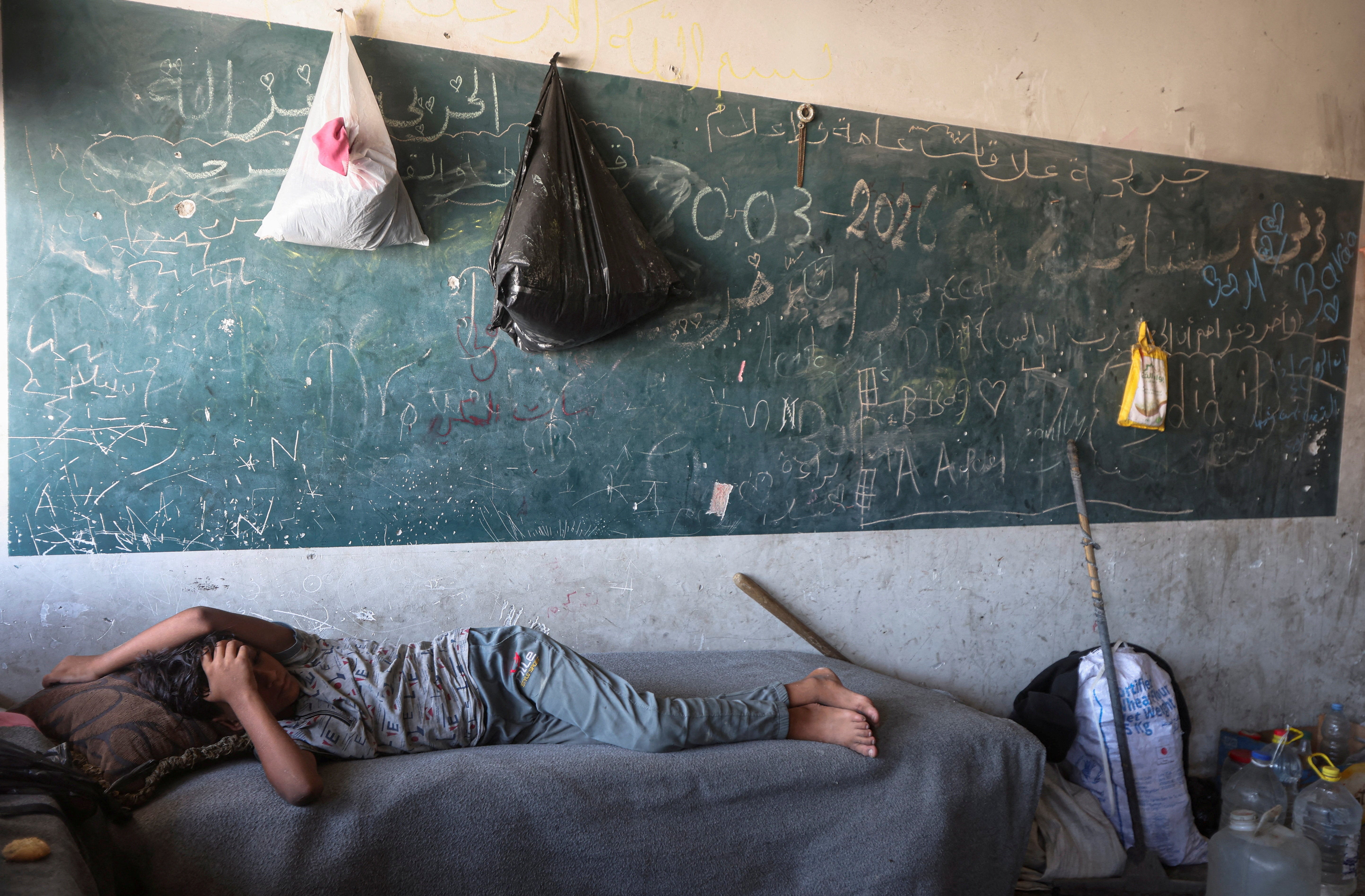 A displaced Palestinian child lies inside a classroom-turned-shelter in Khan Younis, in the southern Gaza Strip, September 10, 2026