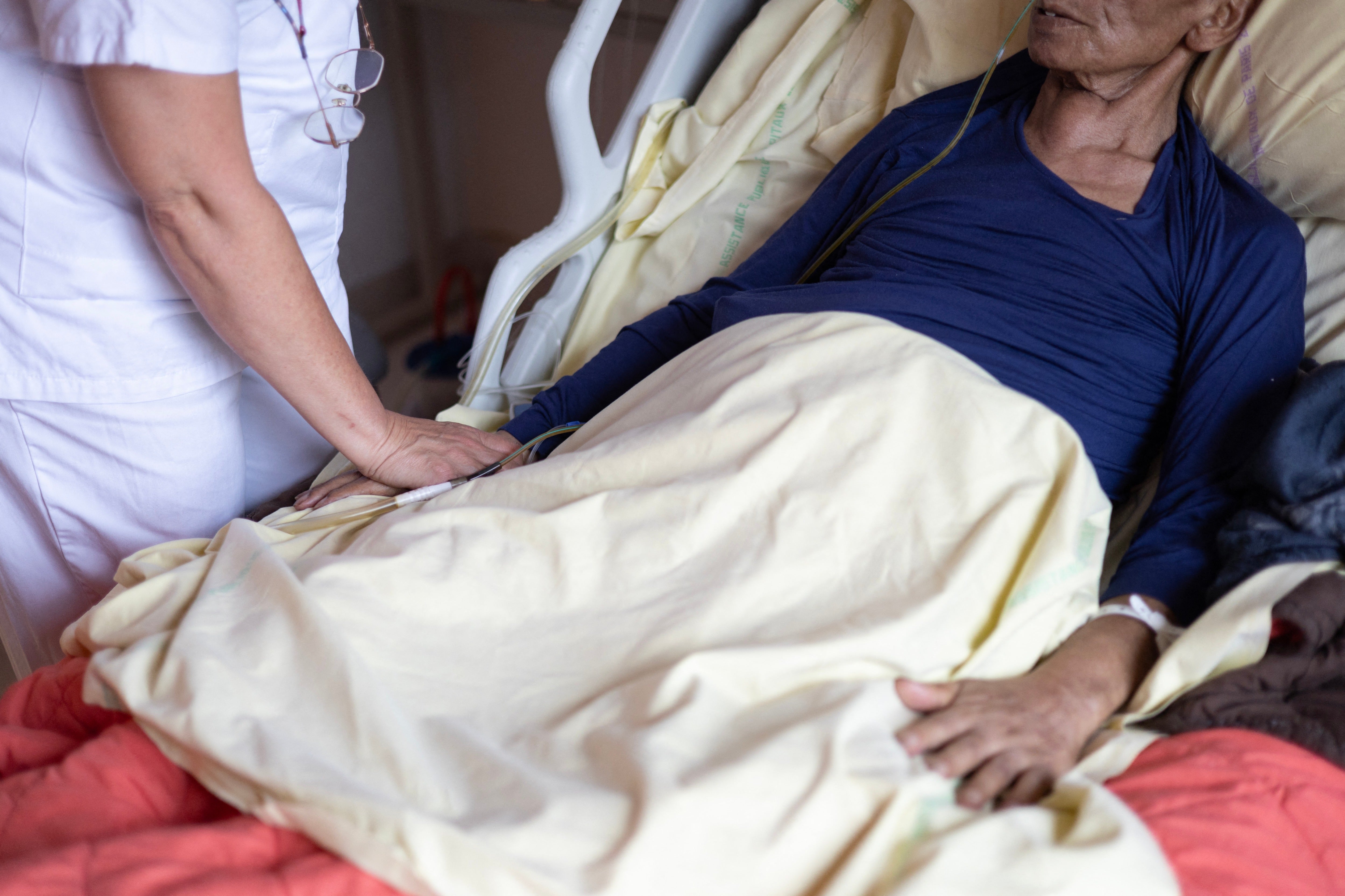 A nurse holds tends to a patient in palliative care