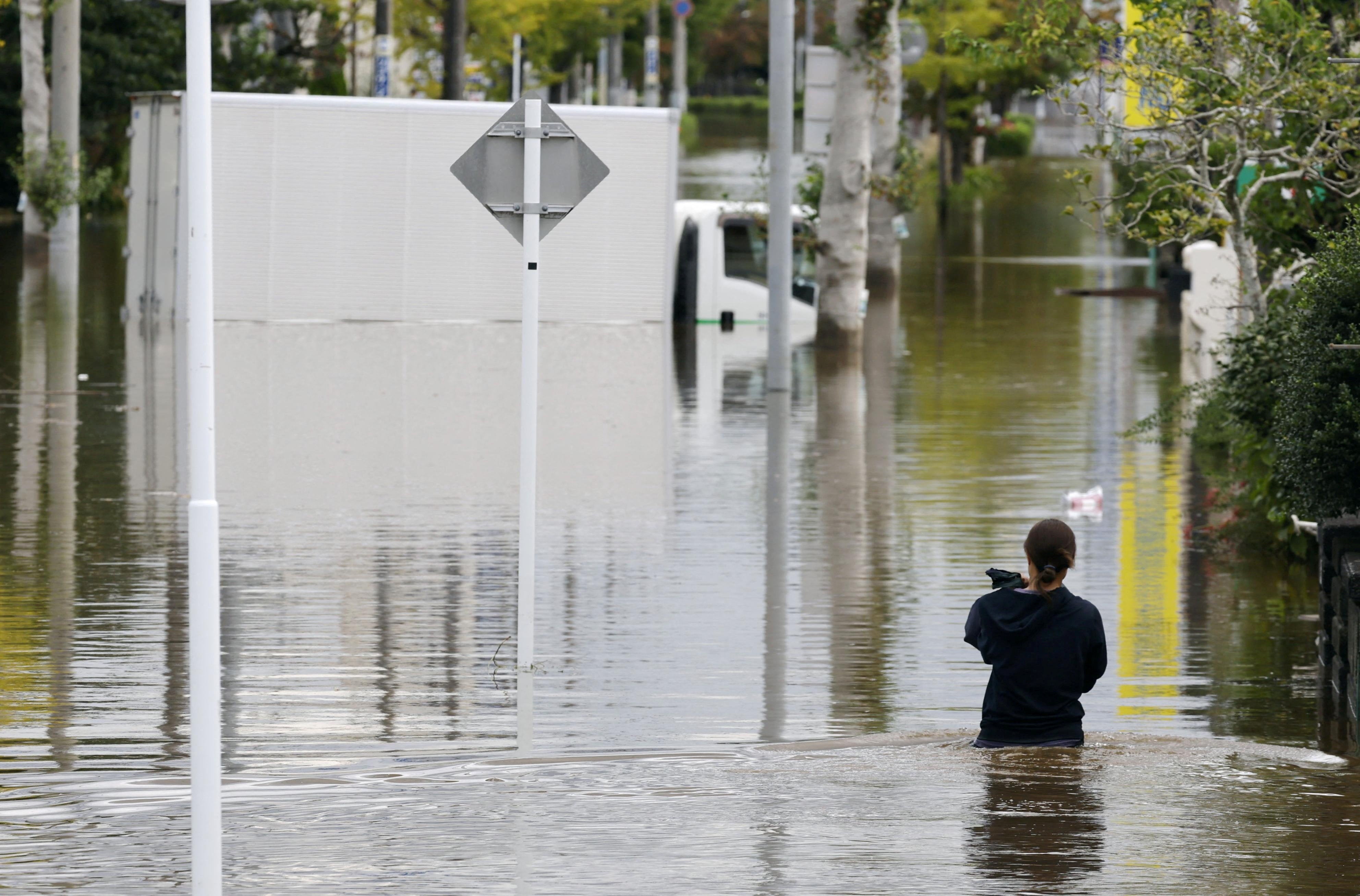 A woman walks at a residential area flooded due to heavy rain caused by Typhoon Dujuan in Sakura, Chiba Prefecture, Japan, 22 September 2026, in this photo taken by Kyodo (Reuters)