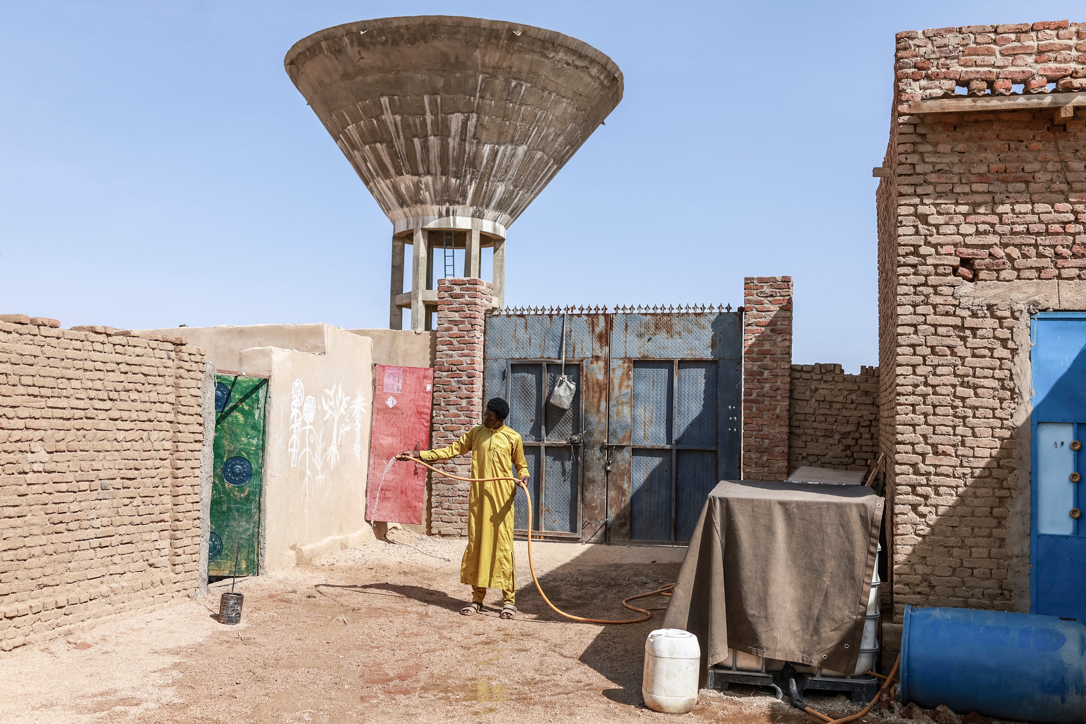 Faisa Ismail holds a water hose in the courtyard of their home in Abeche. In Chad's east, a 'dire need' for water blights lives and fuels deadly violence over access to wells