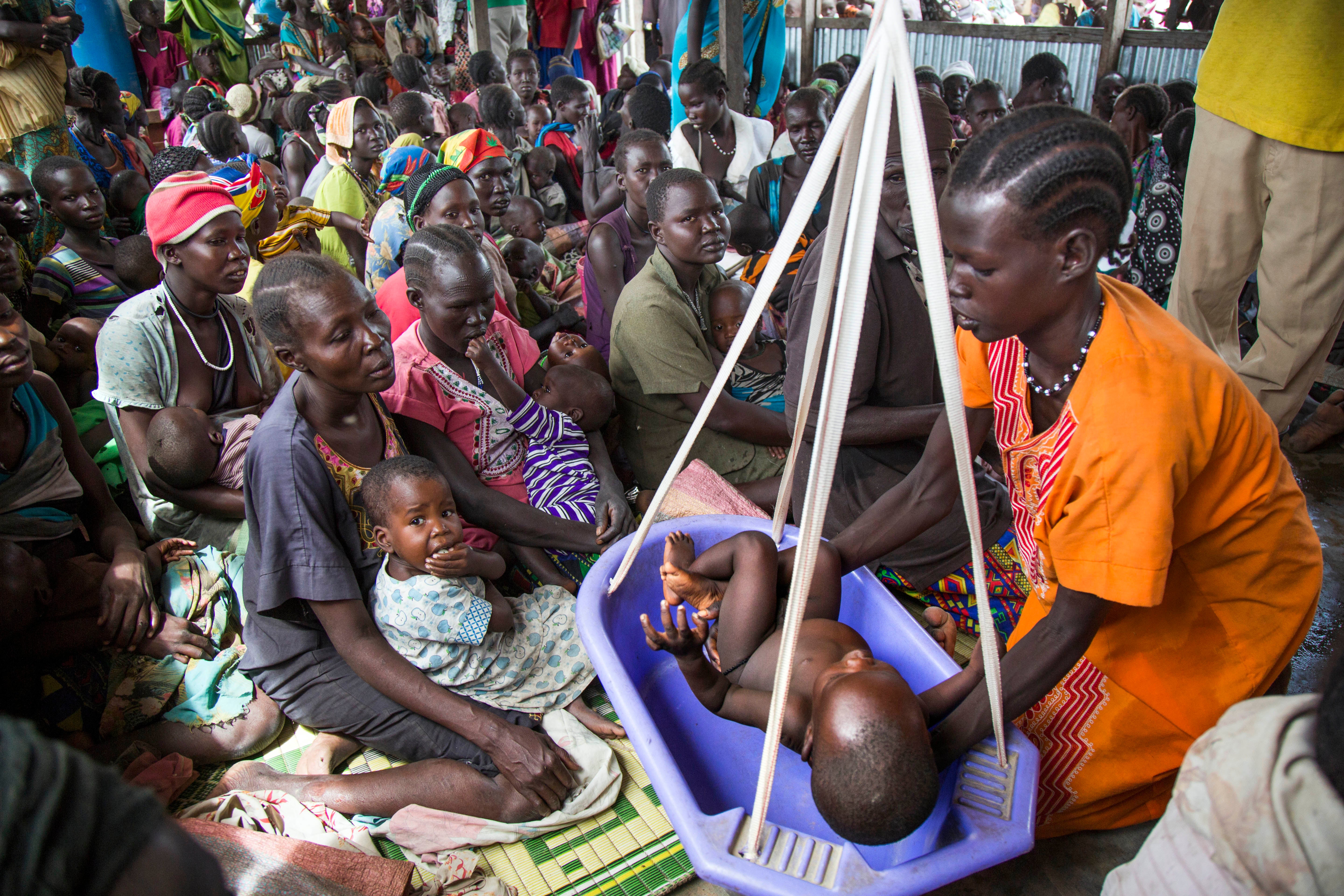 A mother weighs her malnourished child in a nutrition center run by the International Rescue Committee in Panthau, South Sudan, in May 2017. Bordering Sudan is where Miliband says the ‘top humanitarian crisis’ in the world is underway (AFP/Getty)