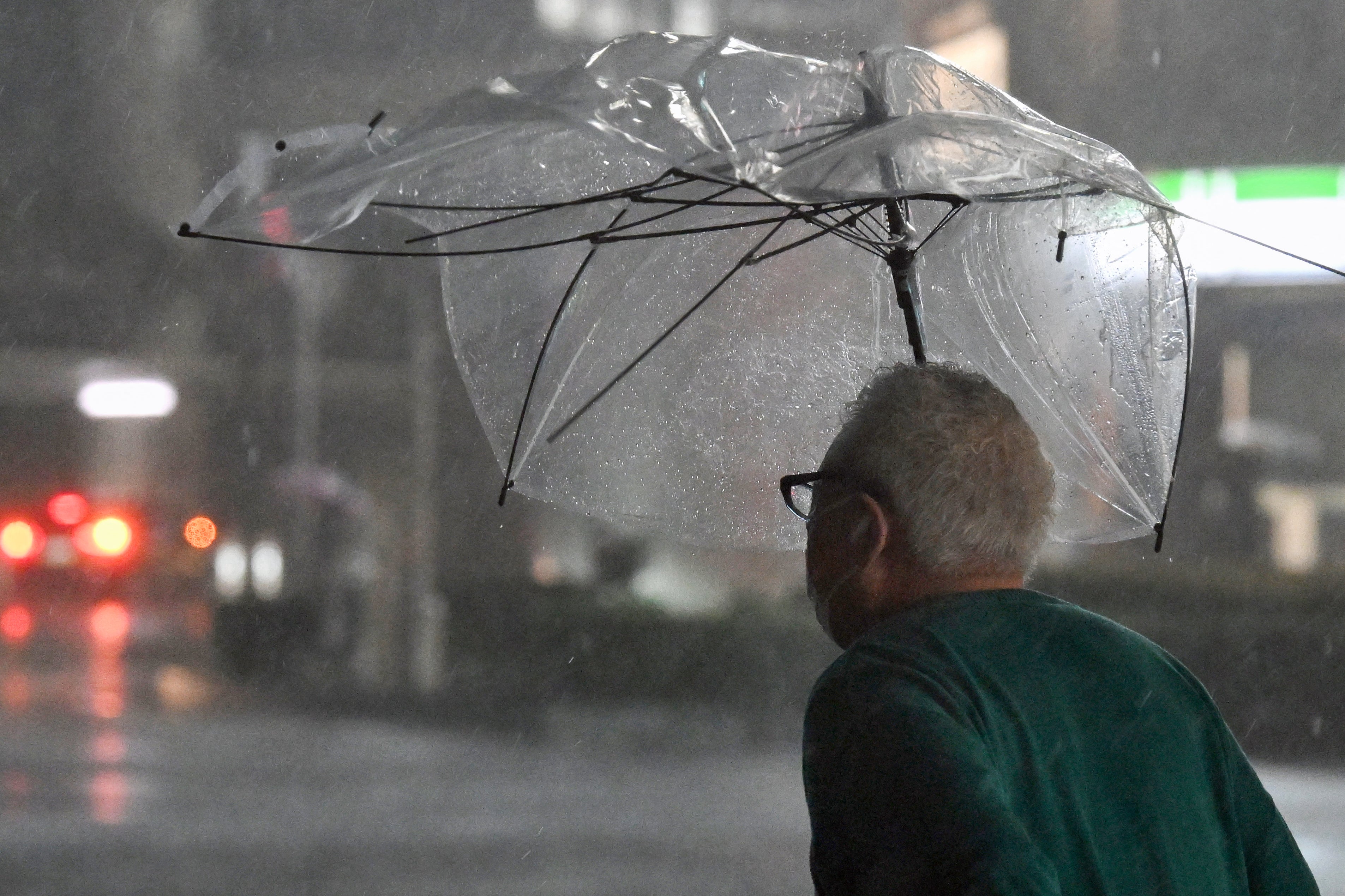 A pedestrian with a broken umbrella walks on a street amid heavy rainfall in Chiba on September 21, 2026 (AFP/Getty)