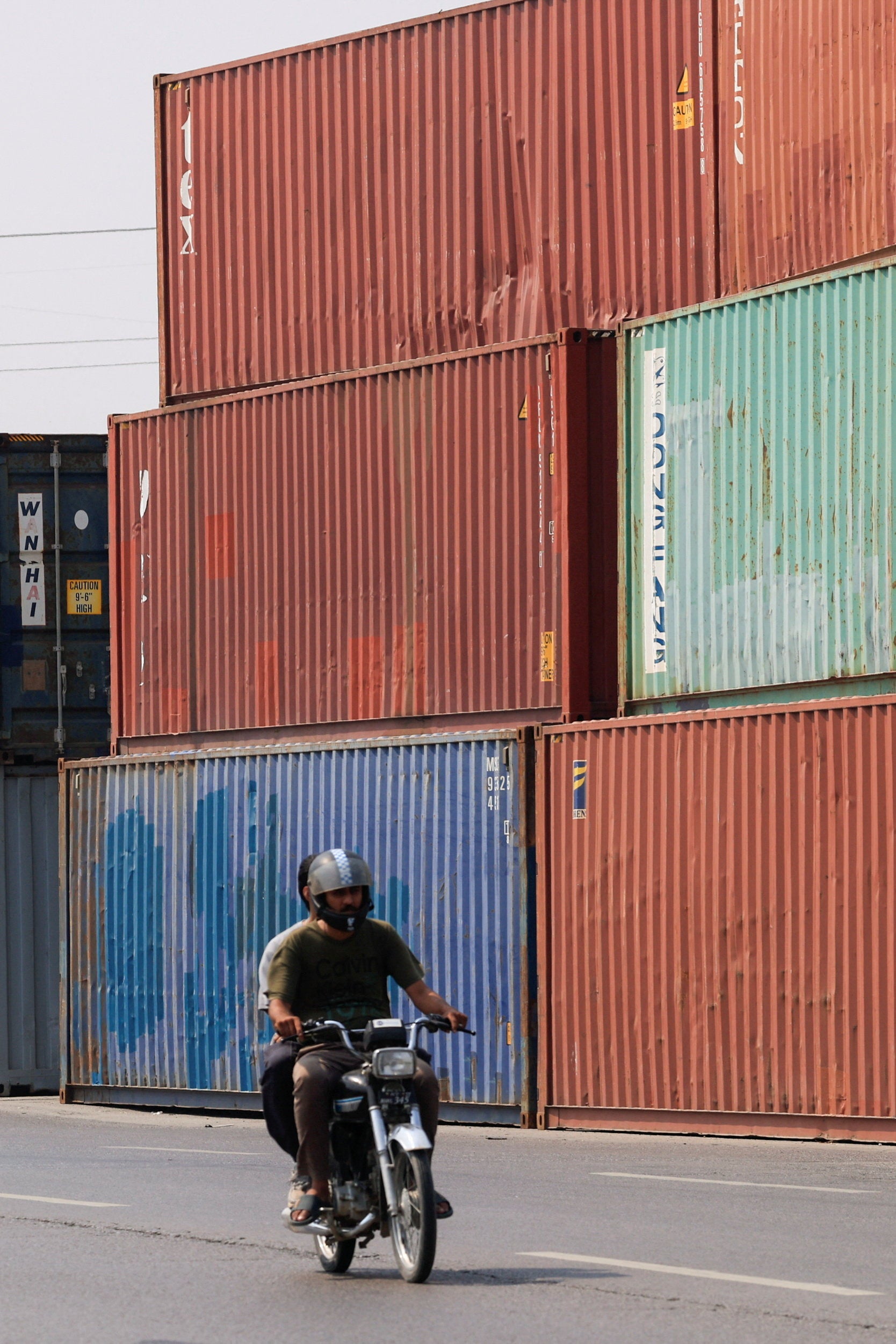 A man rides a motorcycle past shipping containers used to block the area ahead of a planned march by former Pakistani prime minister Imran Khan's party, demanding his release and calling for the supremacy of the Constitution and restoration of the rule of law across the country, in Islamabad, Pakistan, 23 September 2026 (Reuters)