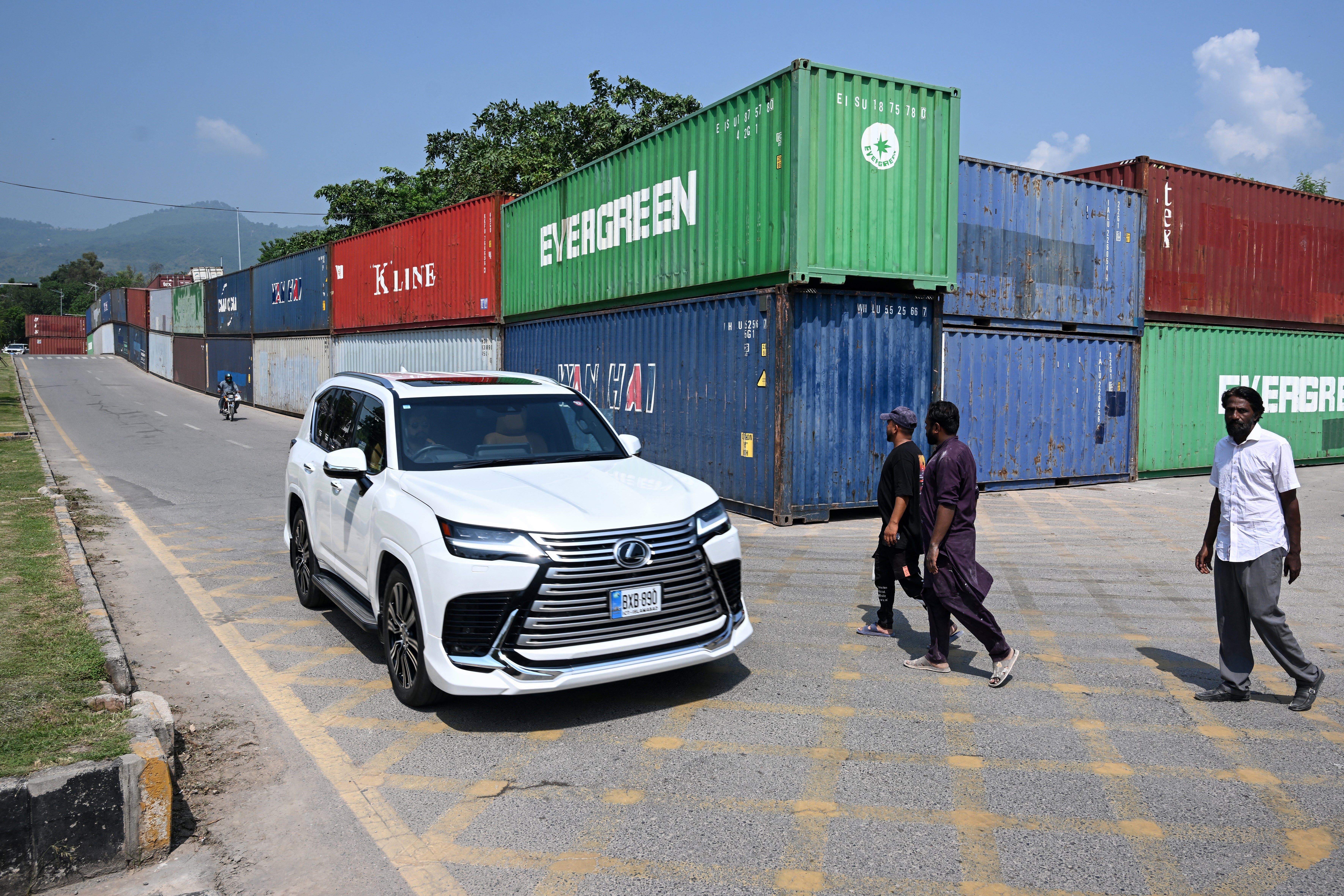 Commuters ride past shipping containers placed around Islamabad's Red Zone on 18 September 2026 ahead of opposition party Pakistan Tehreek-e-Insaf (PTI) protest demanding the release of former prime minister Imran Khan (AFP/Getty)