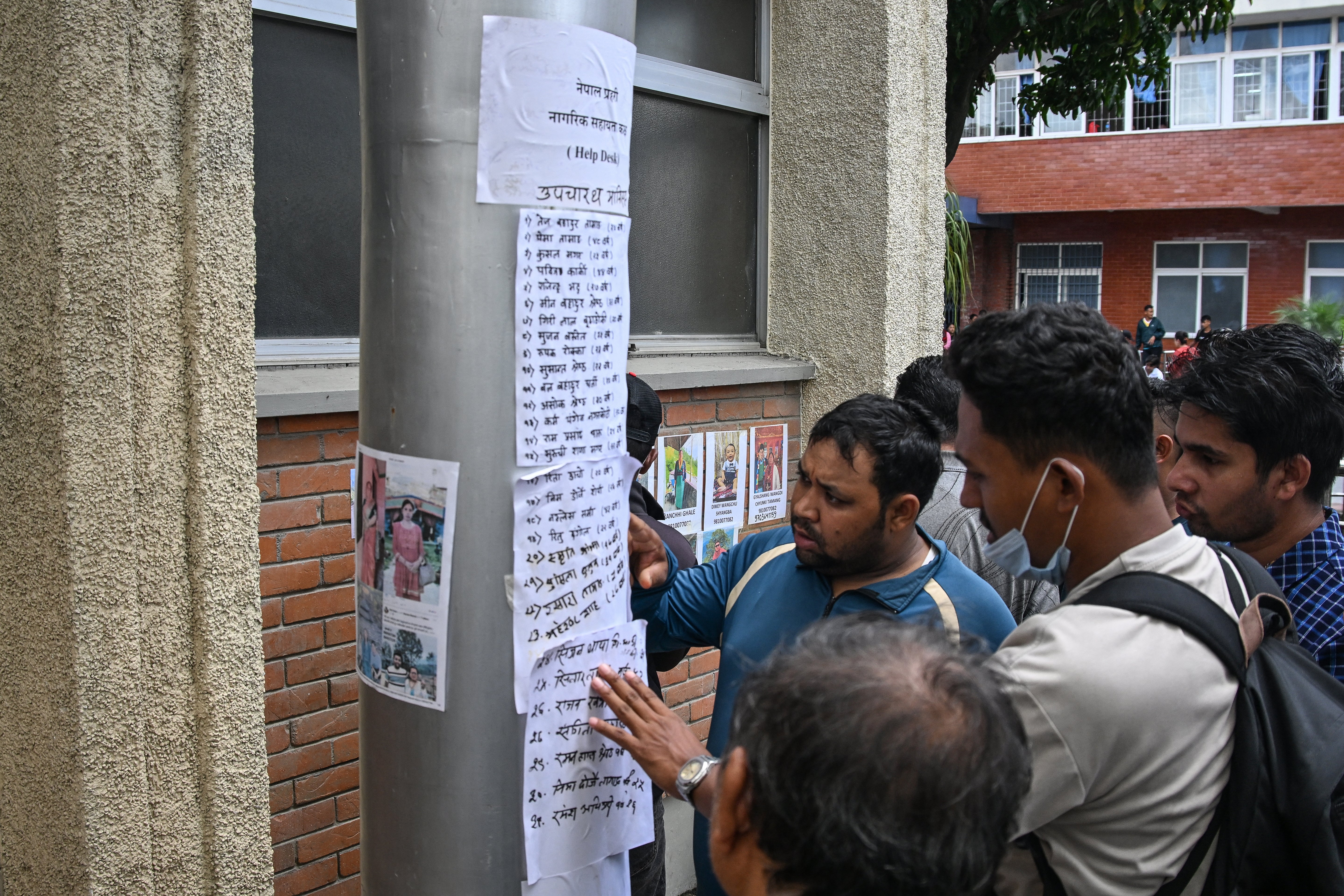 Relatives check the lists of missing people following flash floods in Nepal, outside a hospital in Kathmandu (AFP/Getty)