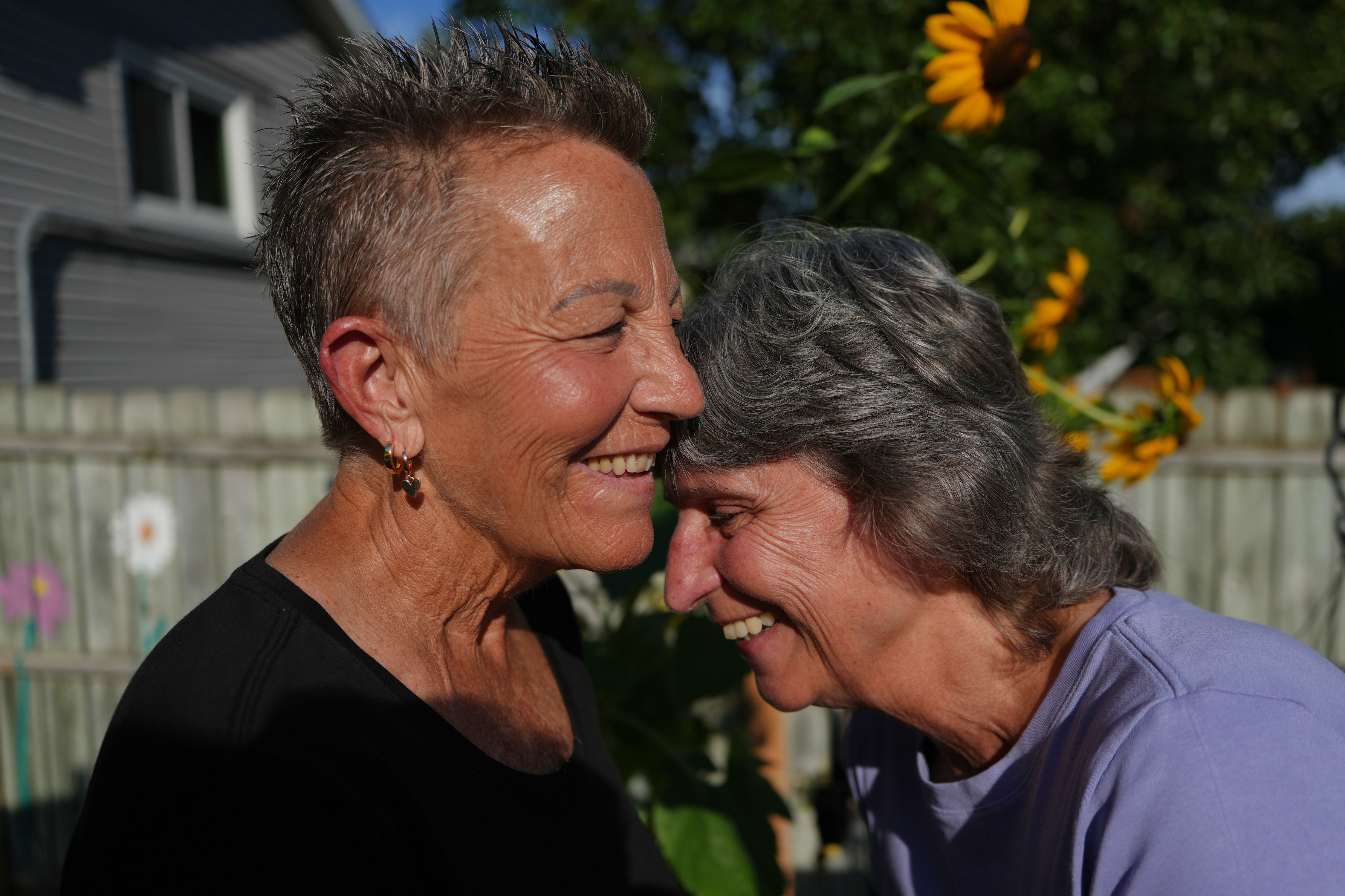Deb Robertson, left, and her wife, Kate Koubek, laugh in the backyard of their home in Lombard, Ill., on Tuesday, Sept. 8, 2026