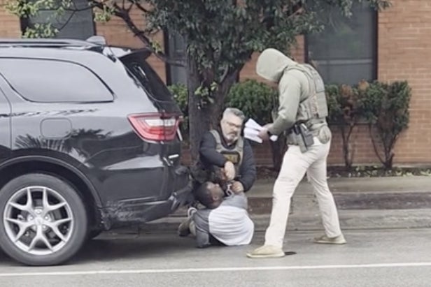 This image taken from video shows a federal officer removing handcuffs from a U.S. citizen after immigration enforcement agents mistook him for a fugitive