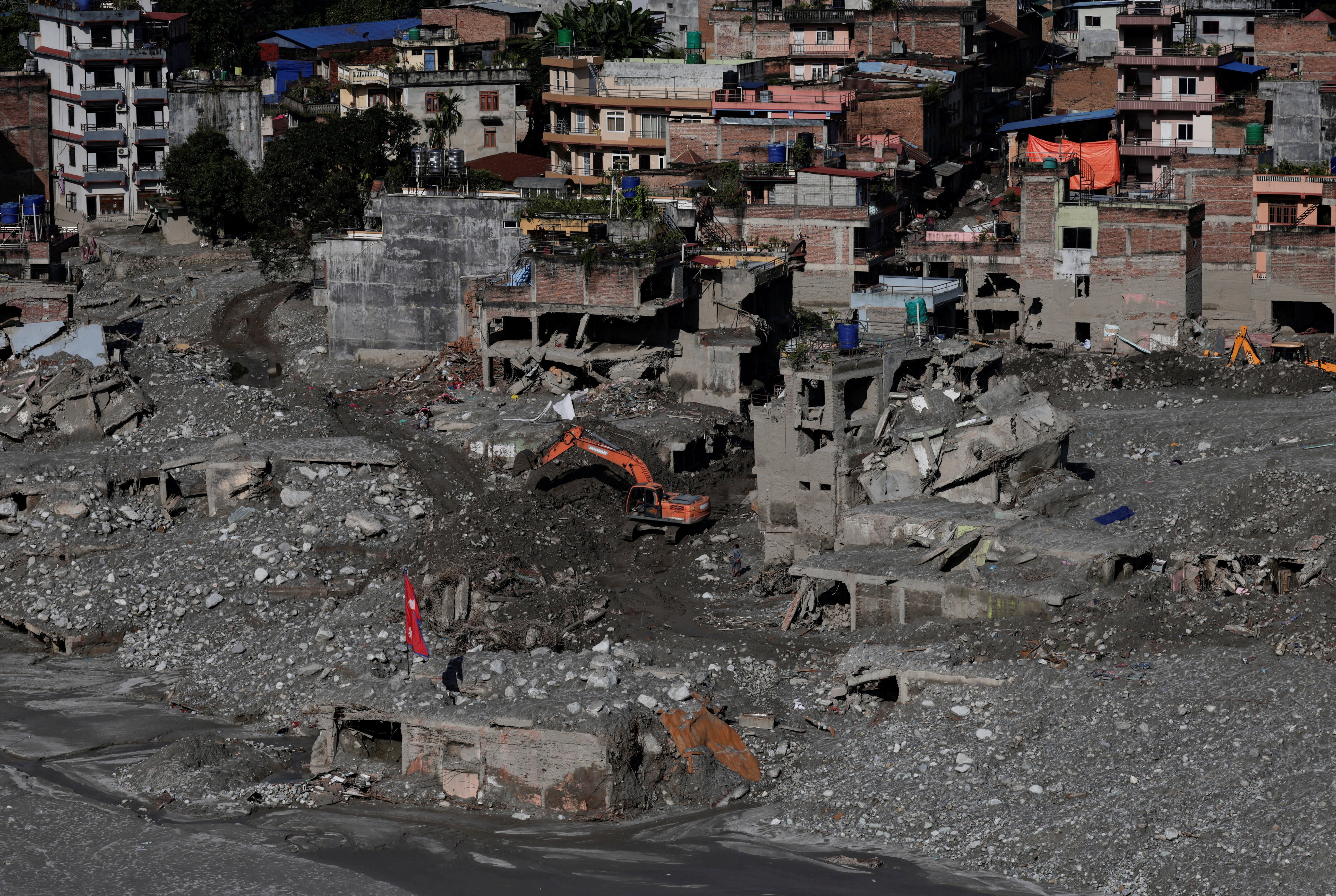 An excavator clears mud from damaged houses following deadly flash floods in Nuwakot, Nepal (Reuters)