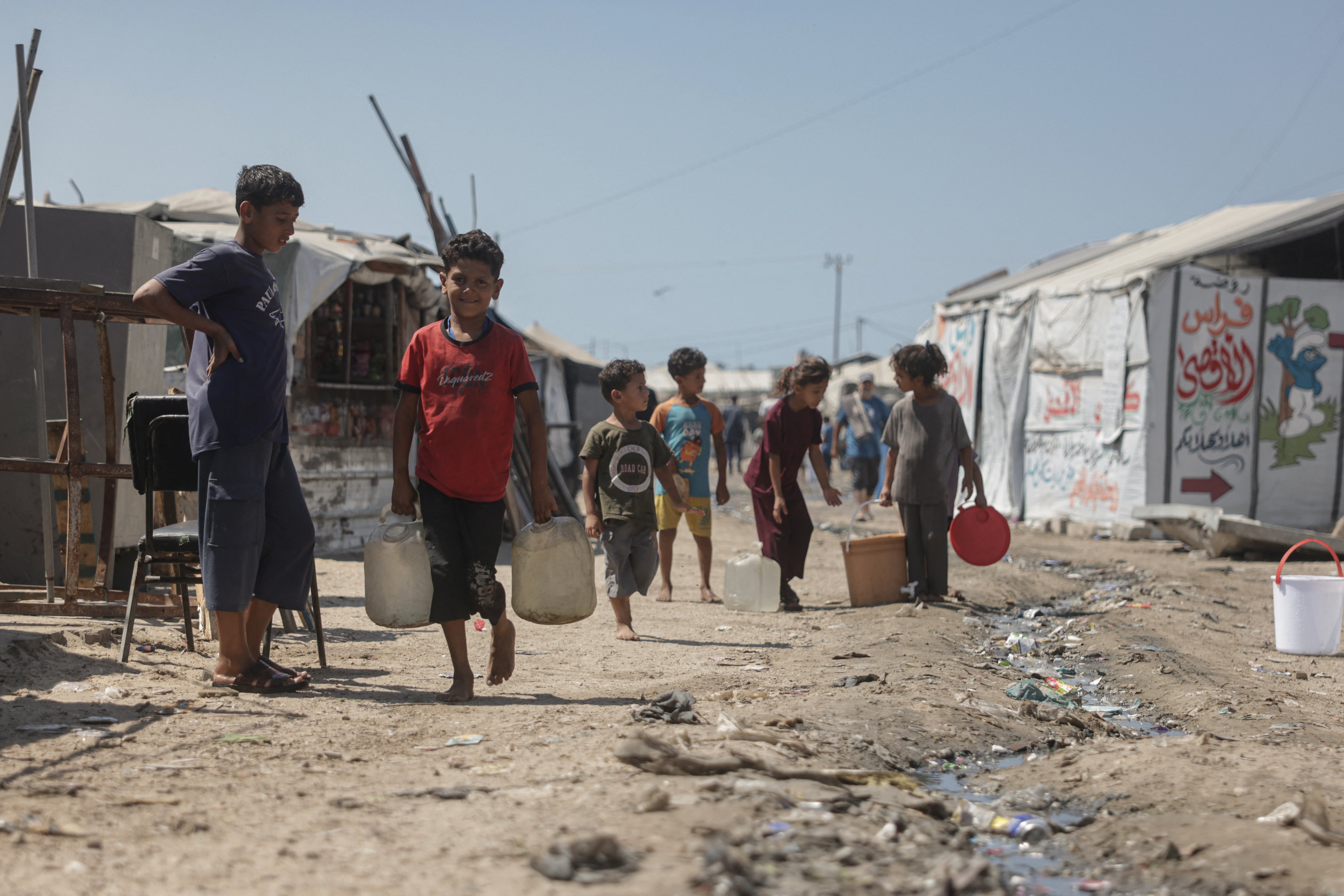 Palestinian children carry water jerrycans past the tents of displaced Palestinians in Al-Mawasi area of Khan Yunis in the southern Gaza Strip on September 25, 2026.